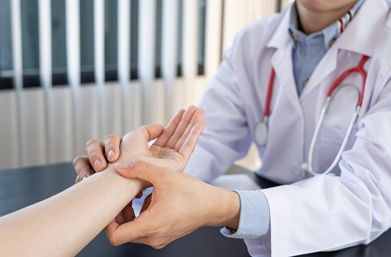 Physiotherapist assessing wrist movement and pain during a clinical examination