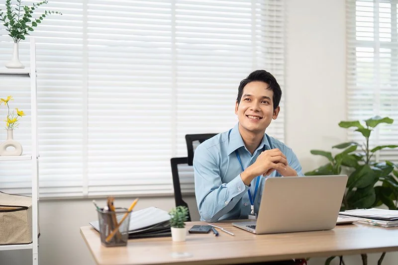 Person sitting at a desk with upright posture and relaxed shoulders while working on a laptop