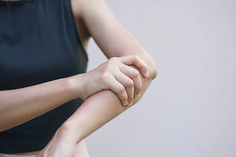 Person holding their elbow due to pain or weakness in the arm