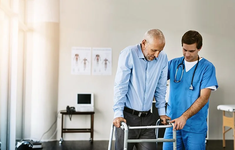 Physiotherapist supporting an older patient during early walking practice after surgery