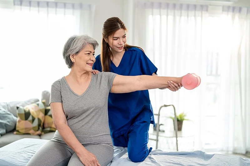Physiotherapist guiding a patient through upper limb rehabilitation exercises using light weights