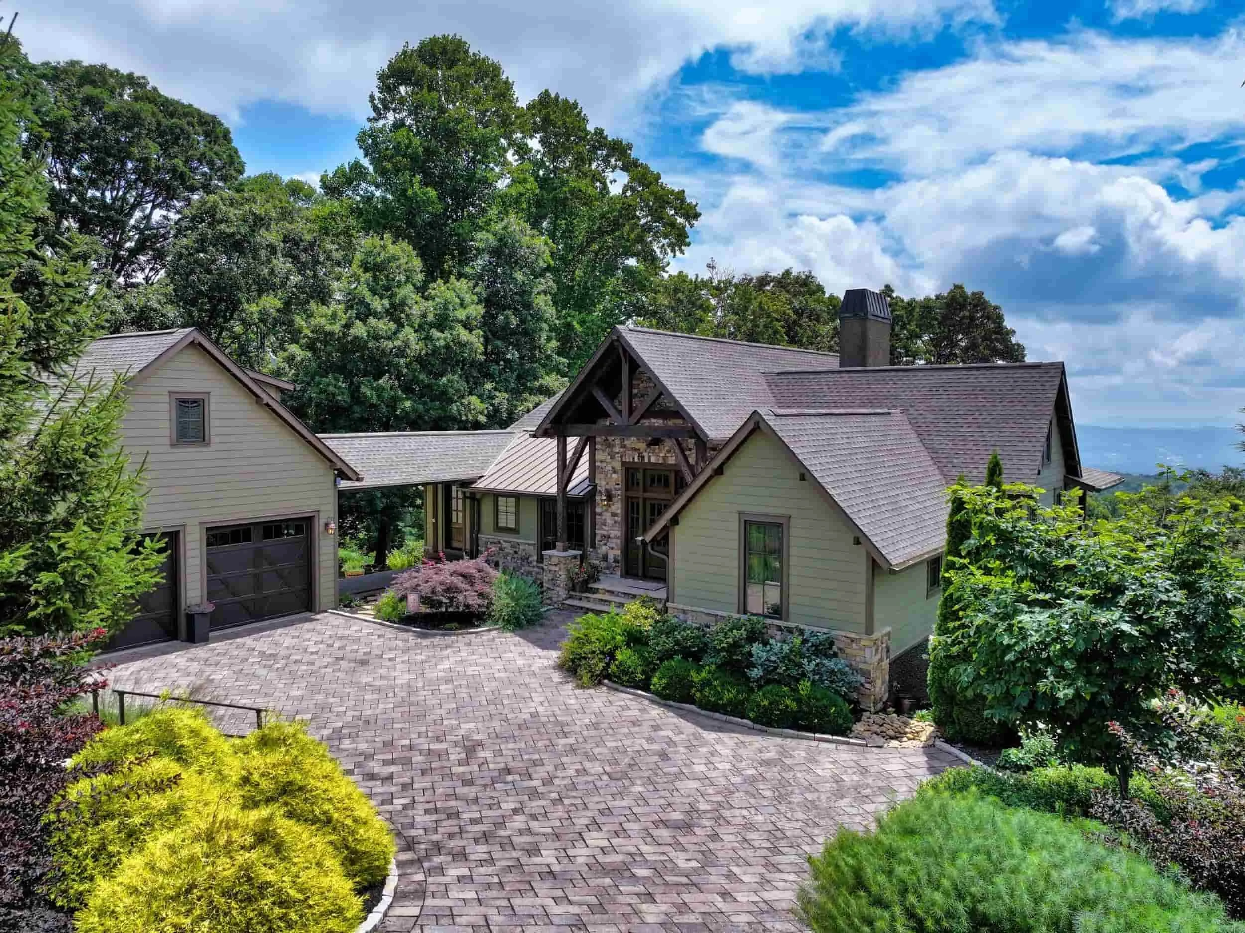 Front view of a timber frame luxury mountain home in Grand Highlands at Bearwallow Mountain Hendersonville NC, with a gabled roof, long range mountain view, and beautiful landscaping. Sold by Ashton Peters Realtor.