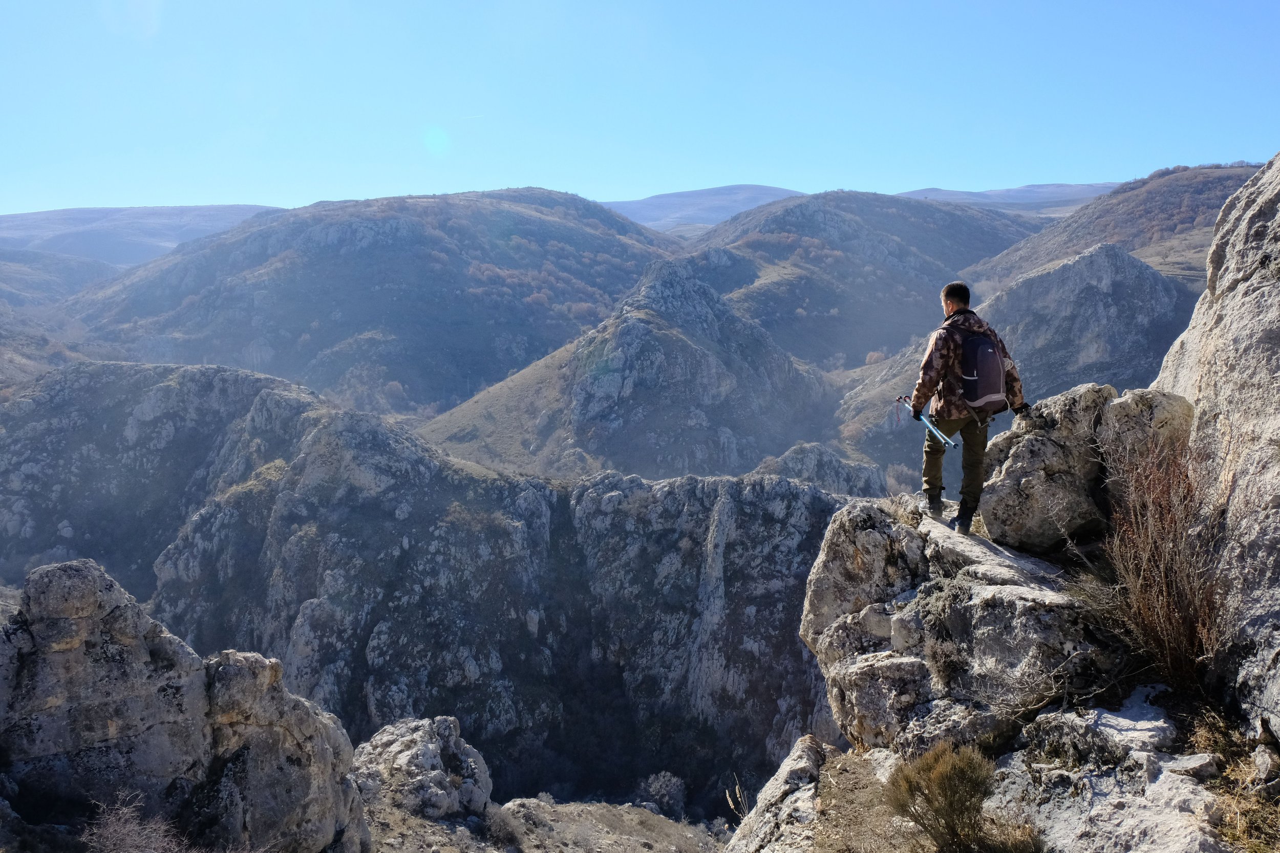 Combat veteran hiking alone on a mountain ridge at dawn, reflecting on moral injury and PTSD.