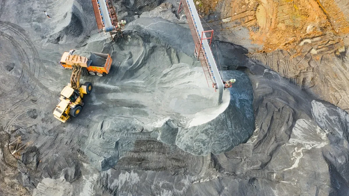 Construction site with a large excavator unloading material onto a cliff