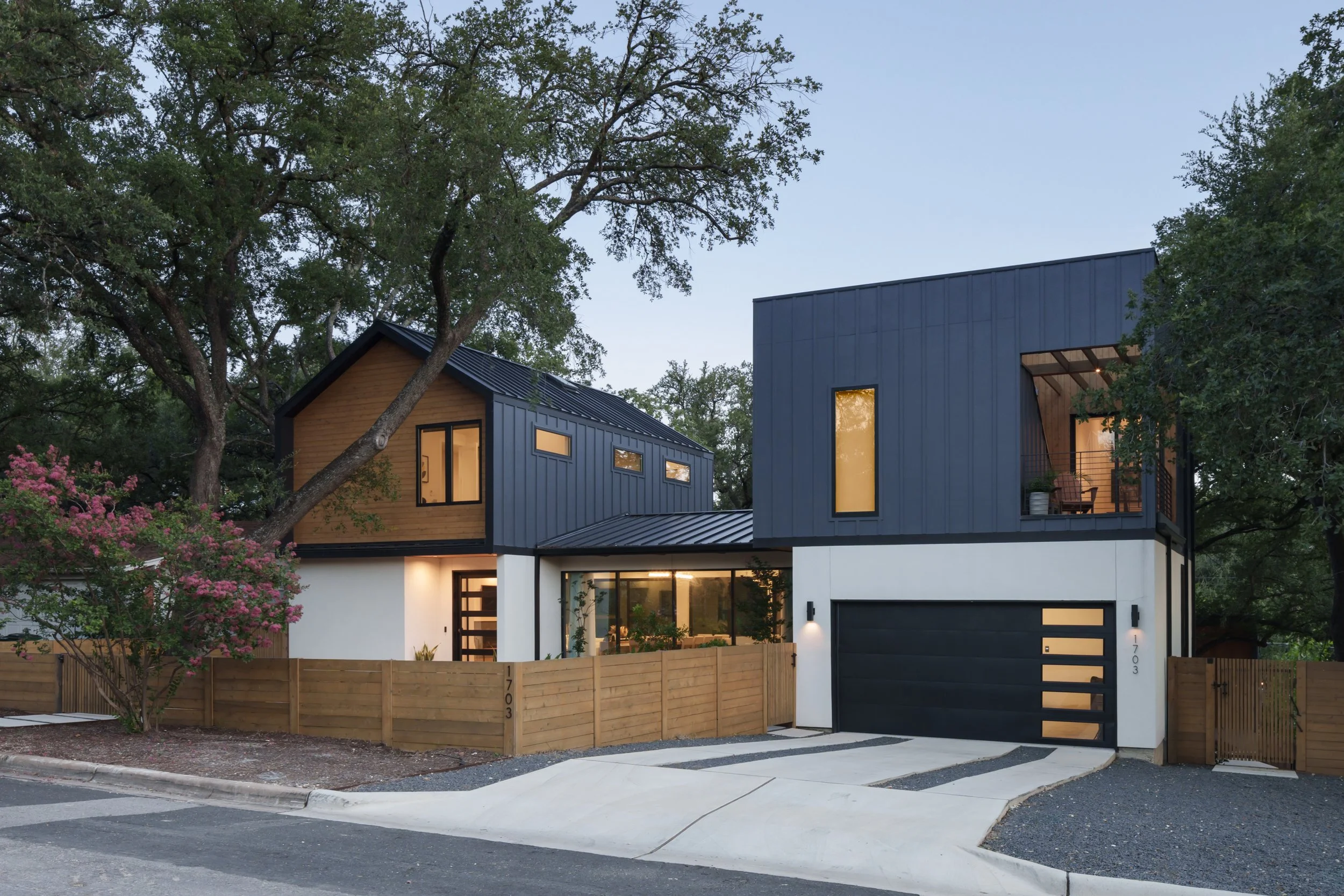 Mariposa Residence by Forsite Studio — front elevation
at dusk from the driveway, dark garage door and lit balcony beside a
horizontal cedar fence — Austin, TX