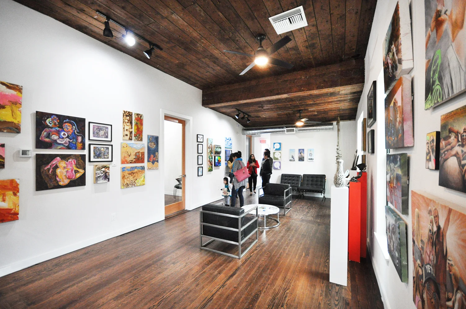 Atelier 1205 gallery by Forsite Studio — art opening with paintings on white walls, wood ceiling, and visitors including children — Austin, TX