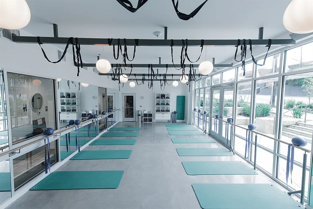 DEFINE South Lamar fitness studio by Forsite Studio — sunlit yoga studio with blue mats, exercise balls, and hanging workout straps — Austin, TX