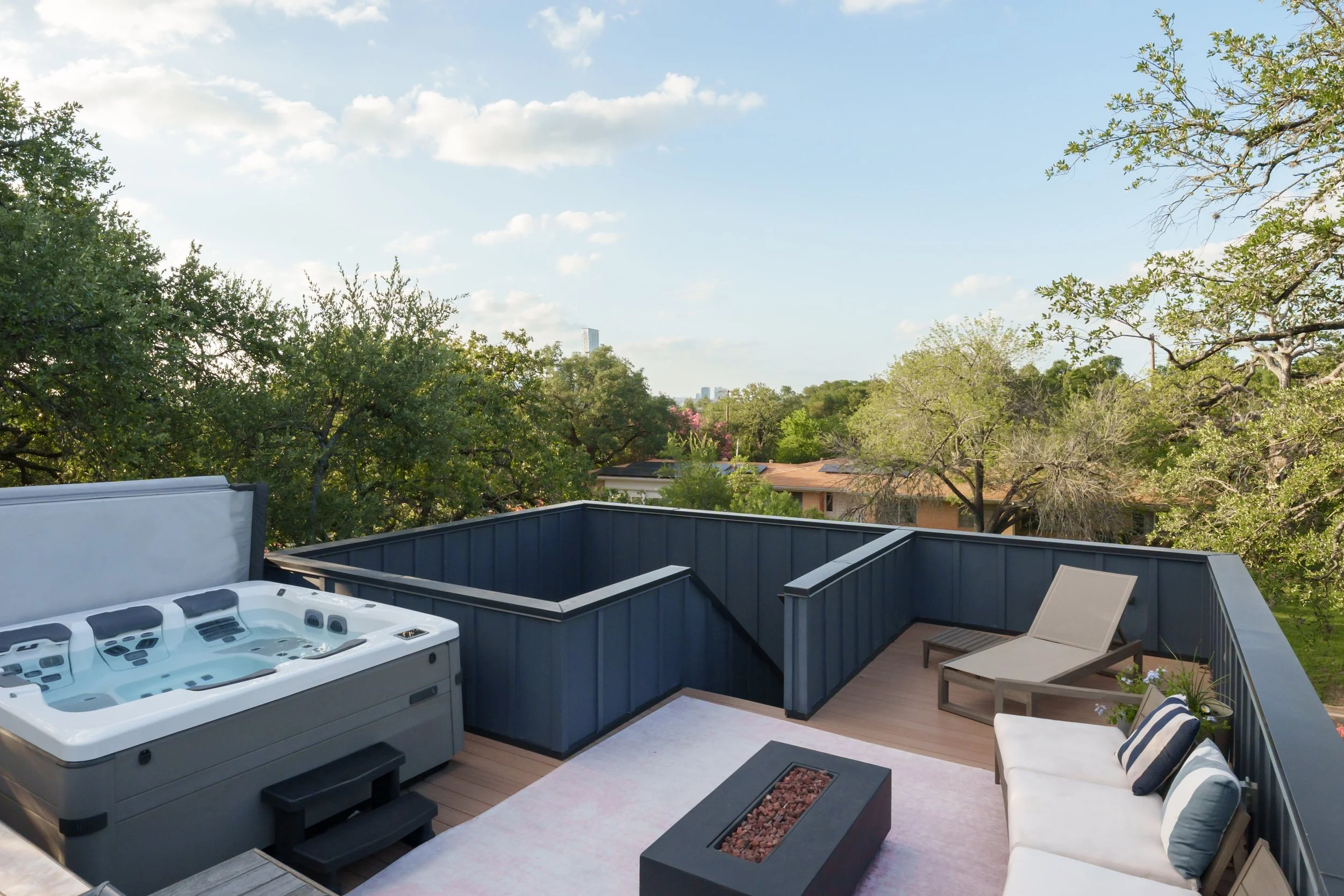 Mariposa Residence by Forsite Studio — roof deck with
hot tub, firepit, and the downtown skyline beyond the tree line —
Austin, TX