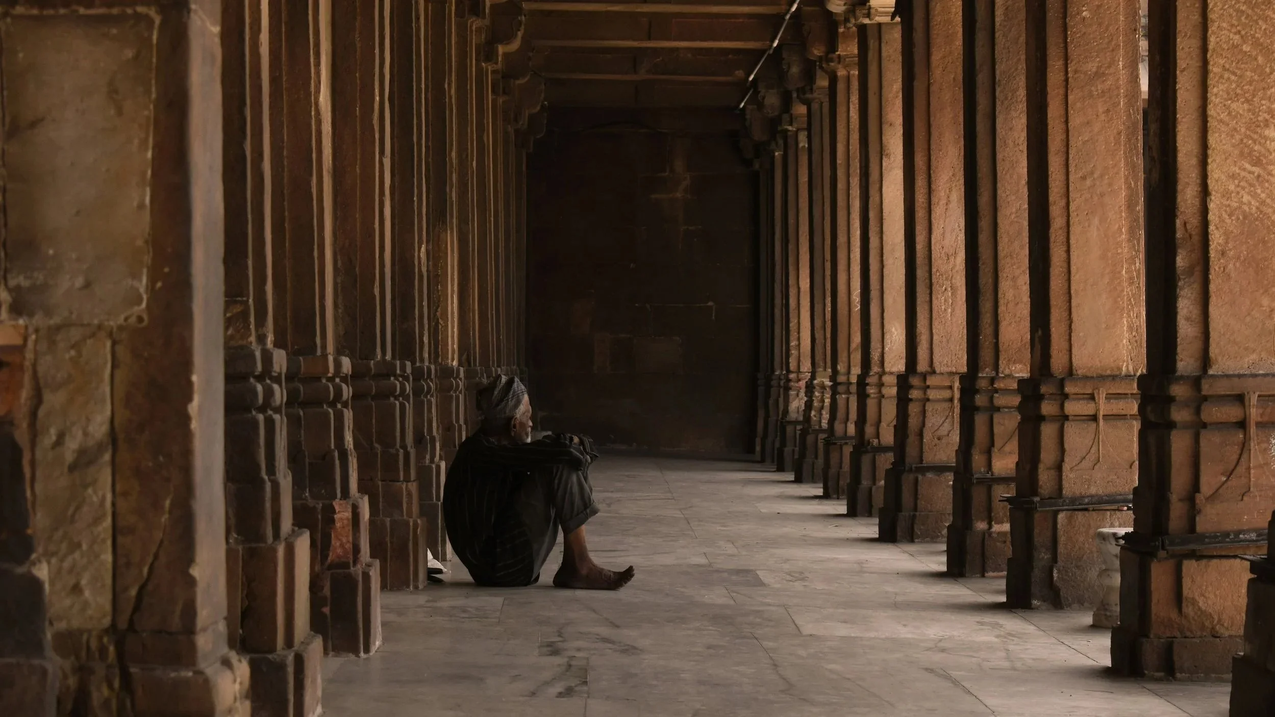 man spending time outside an institution he once trusted and valued where he now feels lonely and isolated due to feeling other after expressing individuality and not fitting the standard systemic follower