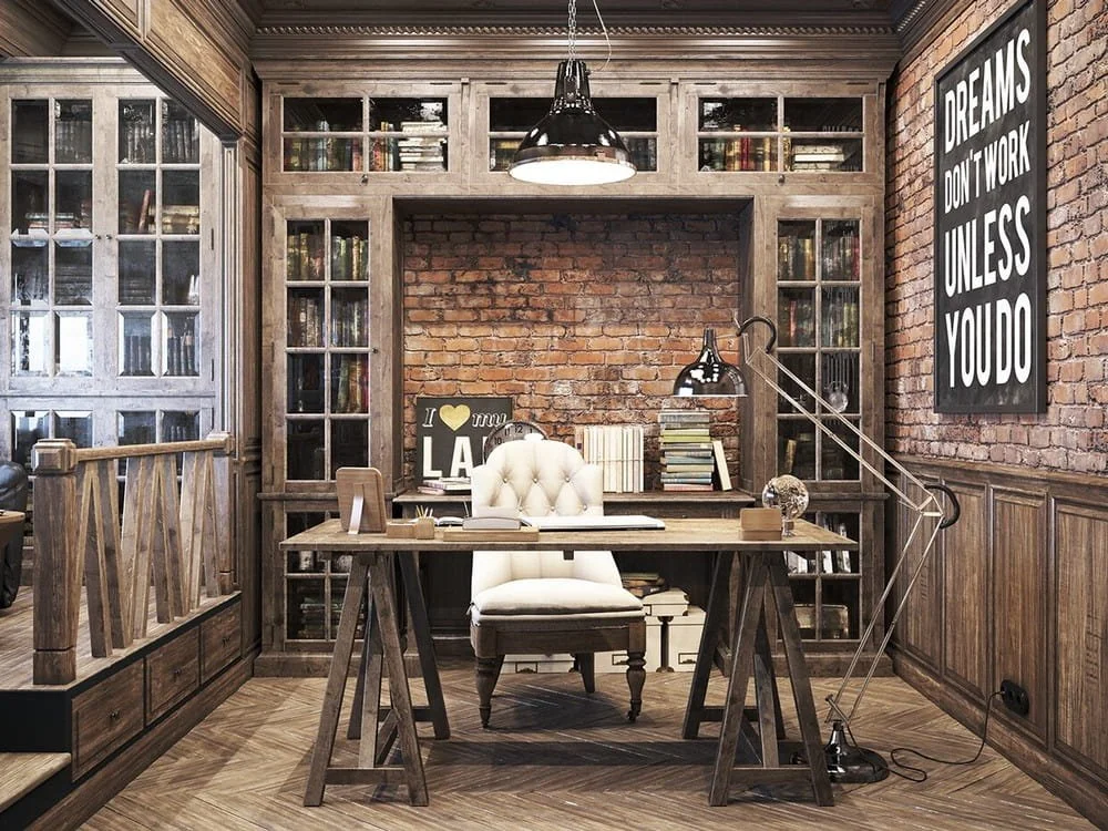 A vintage marketing office with a wooden desk, white tufted office chair, brick wall behind the desk, built-in bookshelves, and a framed quote on the wall reading 'Dreams don't work unless you do.'
