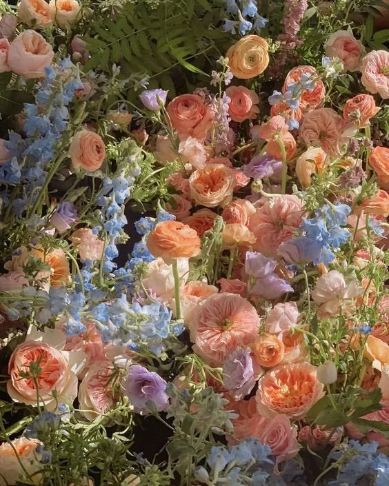 A vibrant assortment of pink, peach, and blue flowers densely packed together.