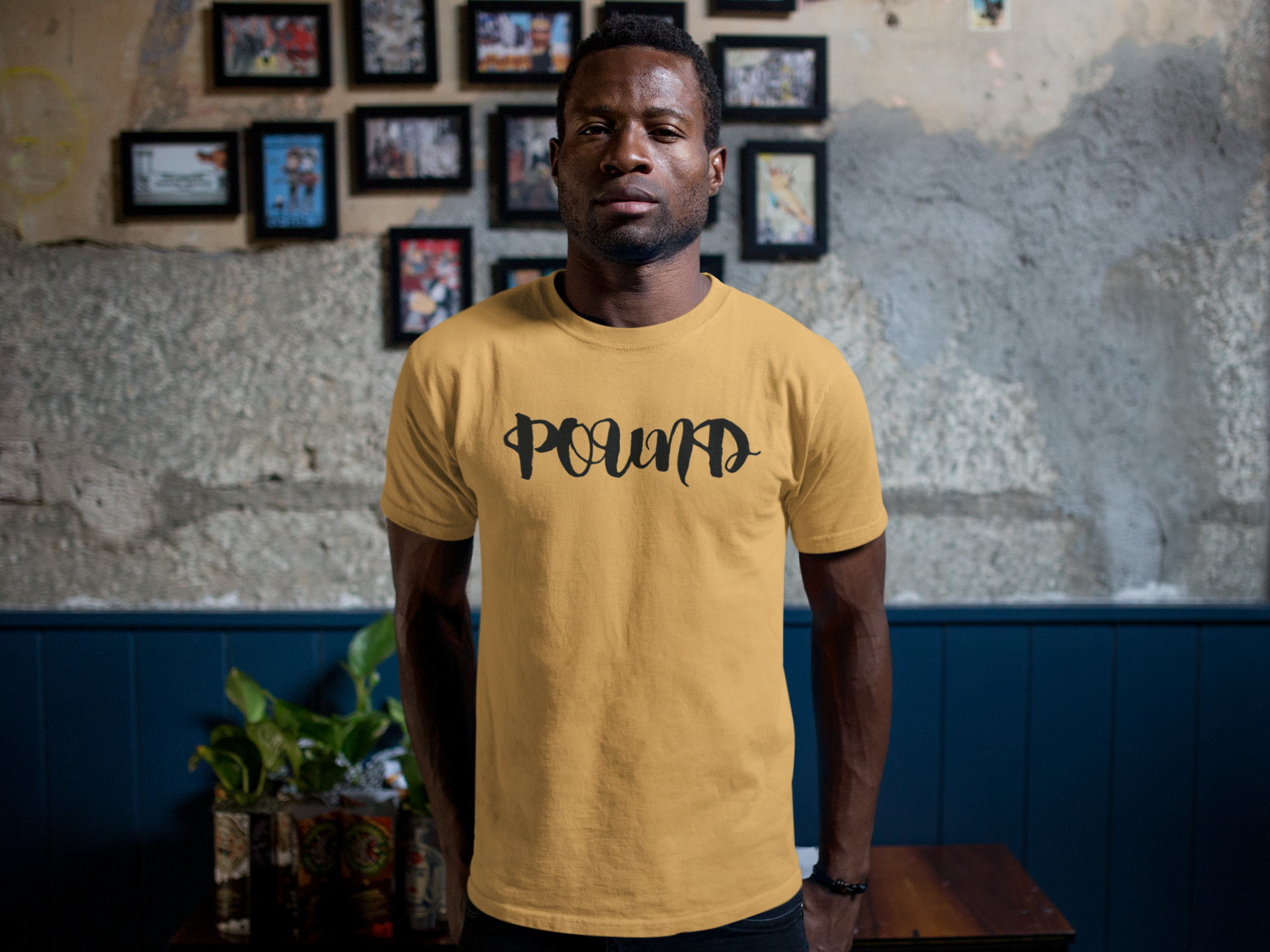 tshirt-mockup-of-a-man-standing-against-a-wall-with-framed-pictures-a17168.png