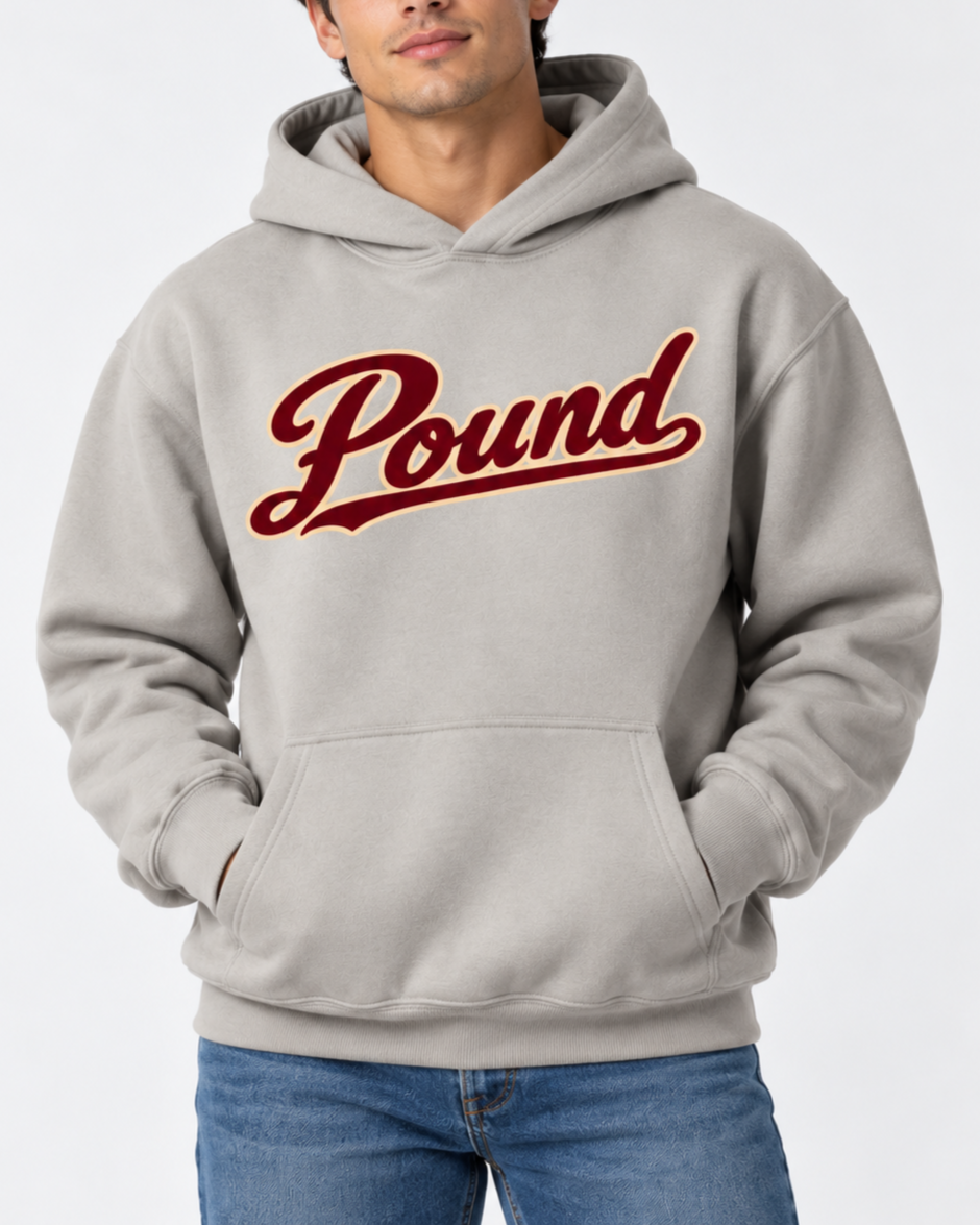 A man is sporting a light gray stone hoodie featuring Pound Script in wine with a cream outline, embodying bold streetwear luxury.