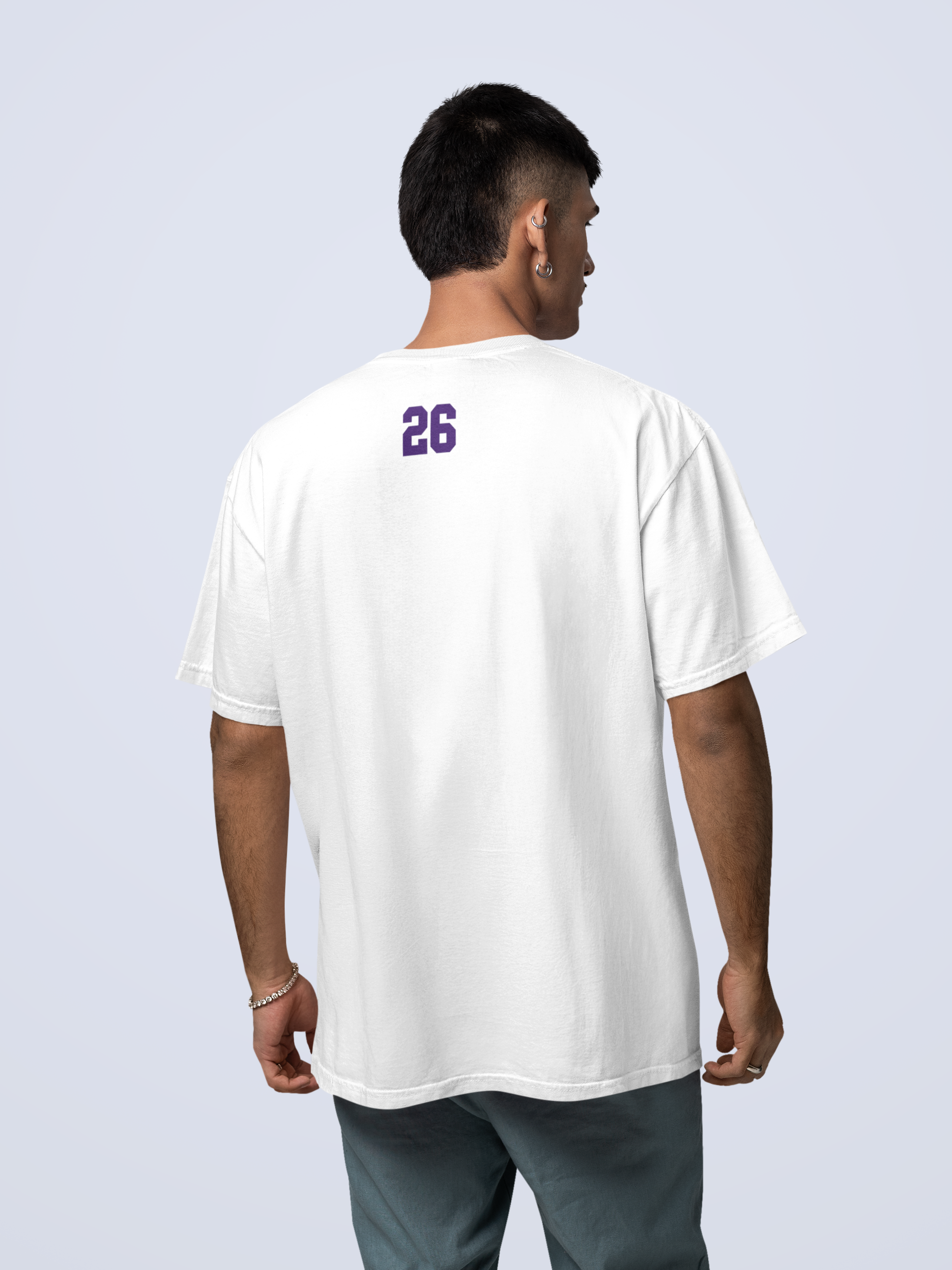 Man standing backwards showing the number 26 on the back of his shirt, oversized tee with short dark hair, wearing a white T-shirt with the word 'pound' printed in Navy Blue, North Hollywood, California, sitting indoors in front of wooden shelves.