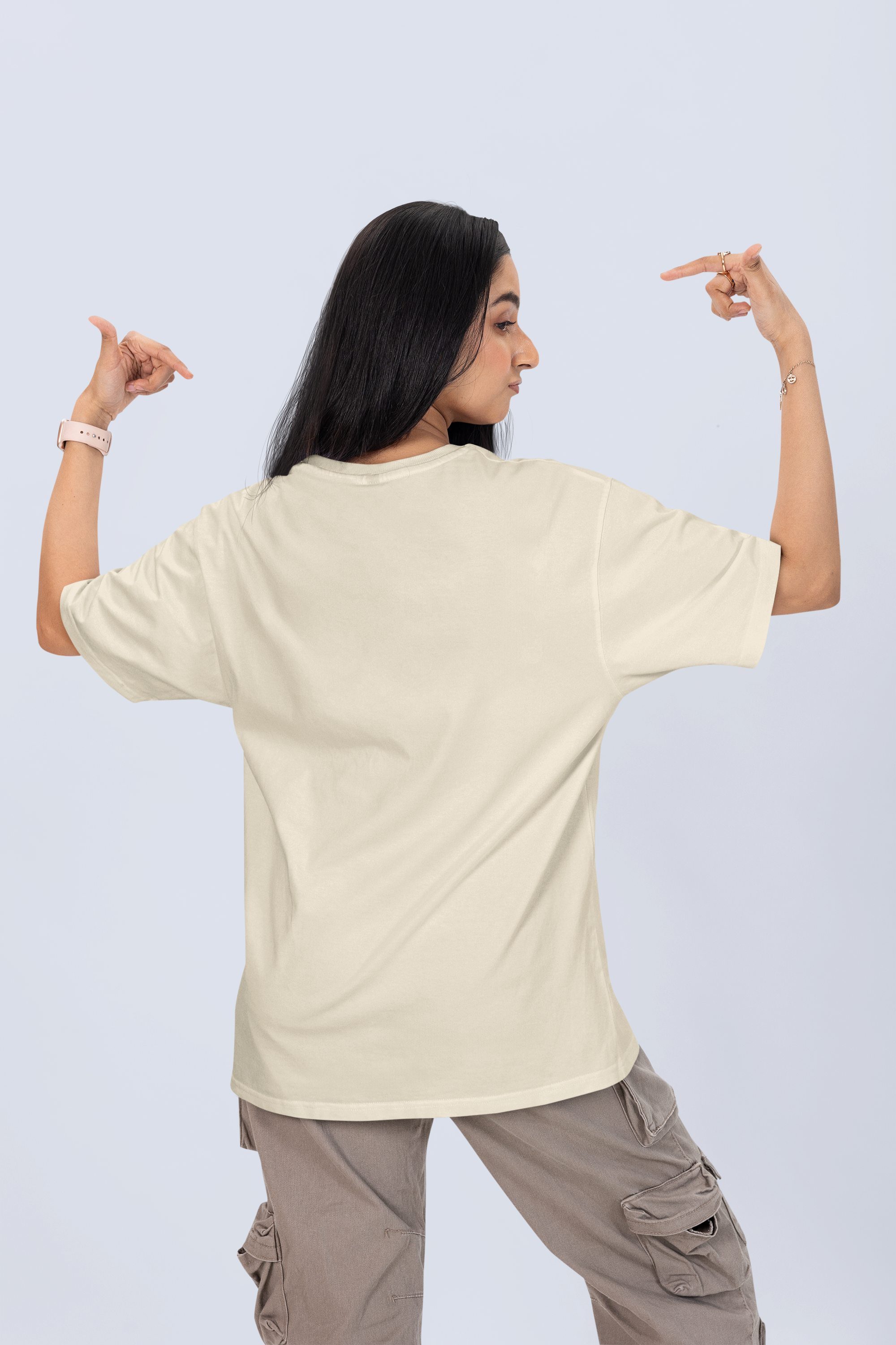 woman standing backwards showing the back of her shirt, oversized tee with short dark hair, wearing a white T-shirt with the word 'pound' printed in Navy Blue, North Hollywood, California, sitting indoors in front of wooden shelves.