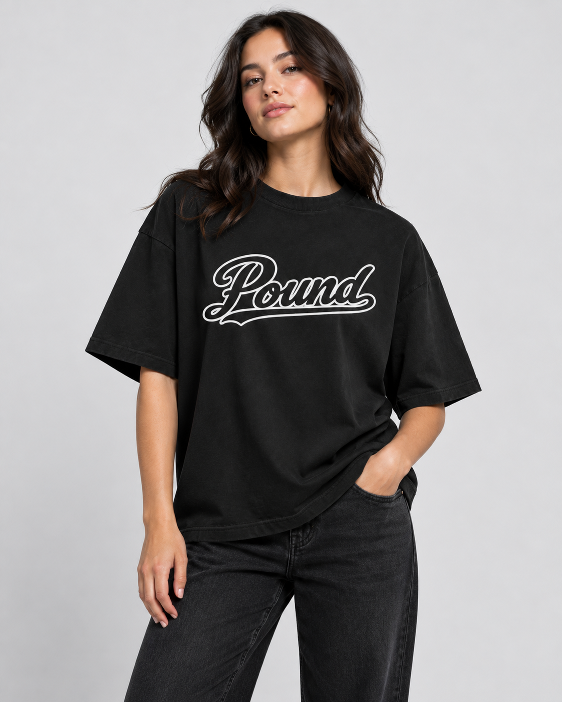 A woman wearing a black t-shirt with the word 'Pound' written in white cursive lettering, standing against a plain light gray background.