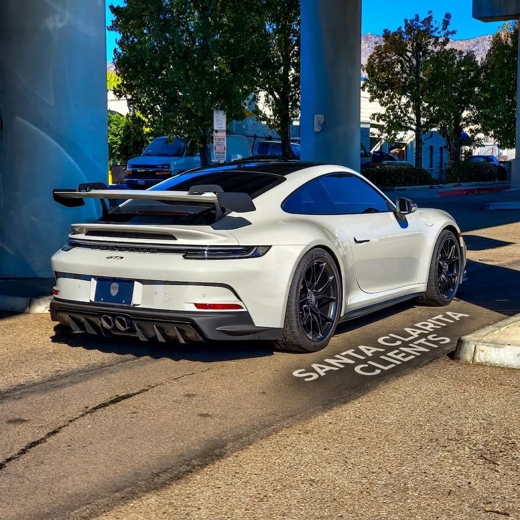 Porsche Gt3 992.2, parked in a marked spot that says 'Santa Clarita Clients' in an outdoor lot with trees and buildings in the background.