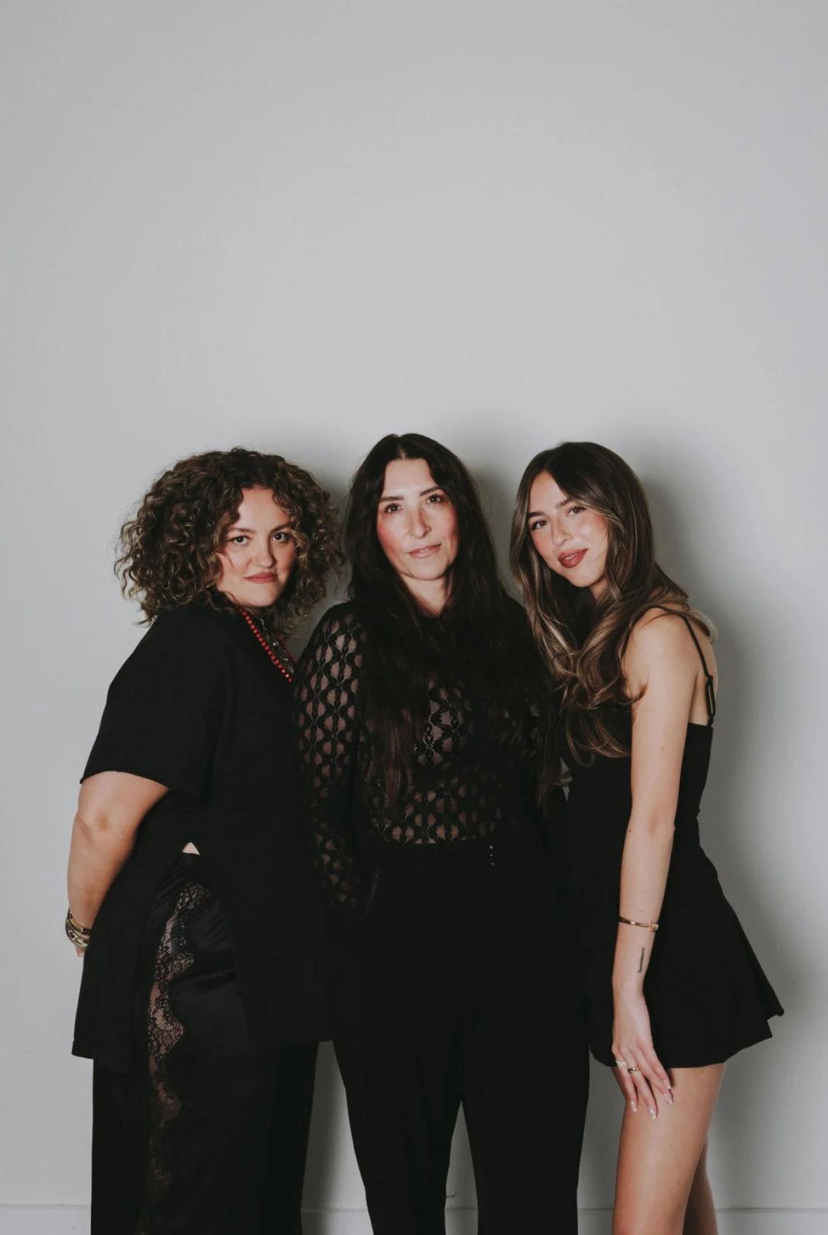 KK Hair Co. hair extension stylists standing together against a light gray wall, dressed in black outfits, posing for the photo.