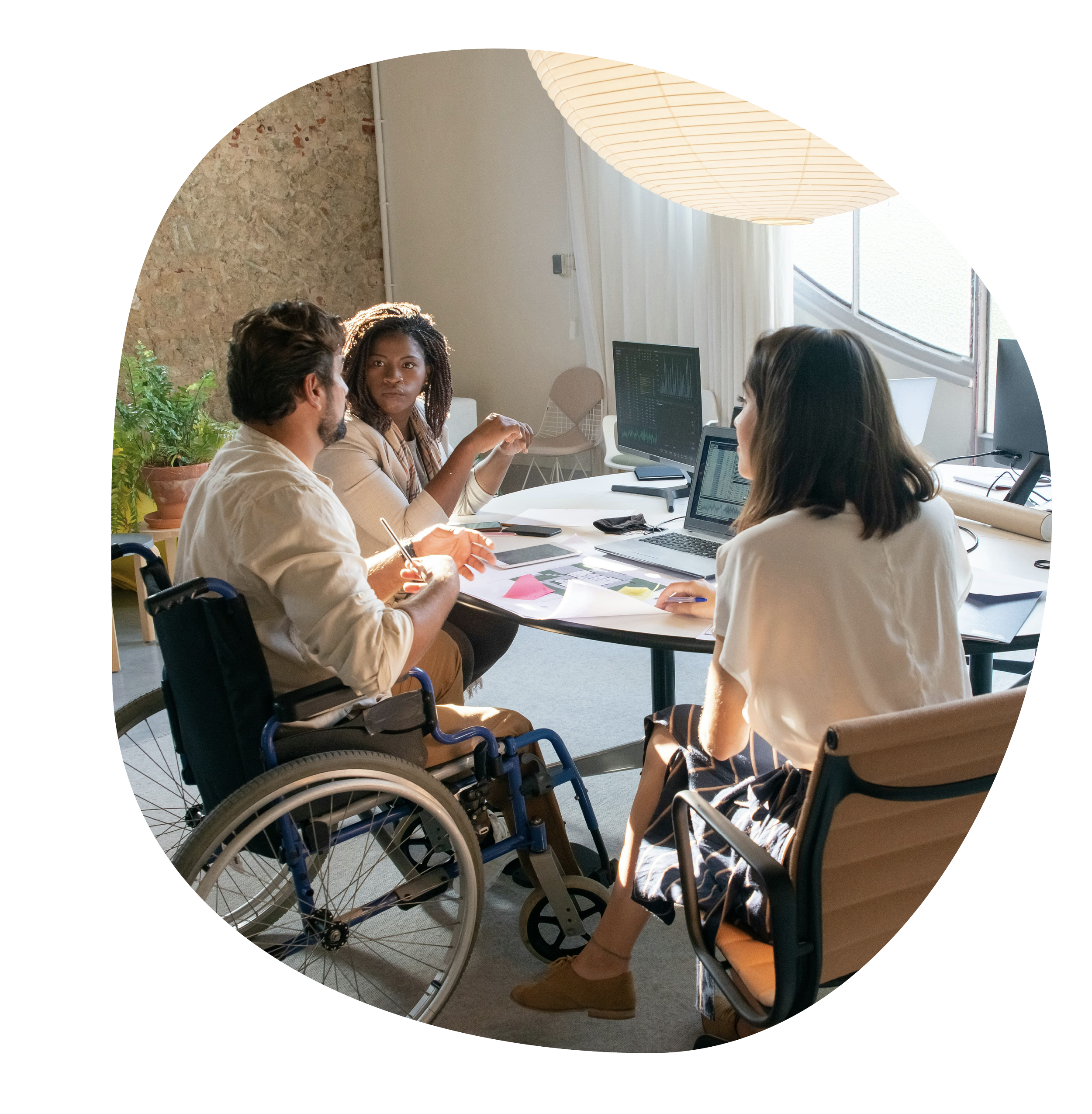 Three people working together in a room, with one person in a wheelchair.