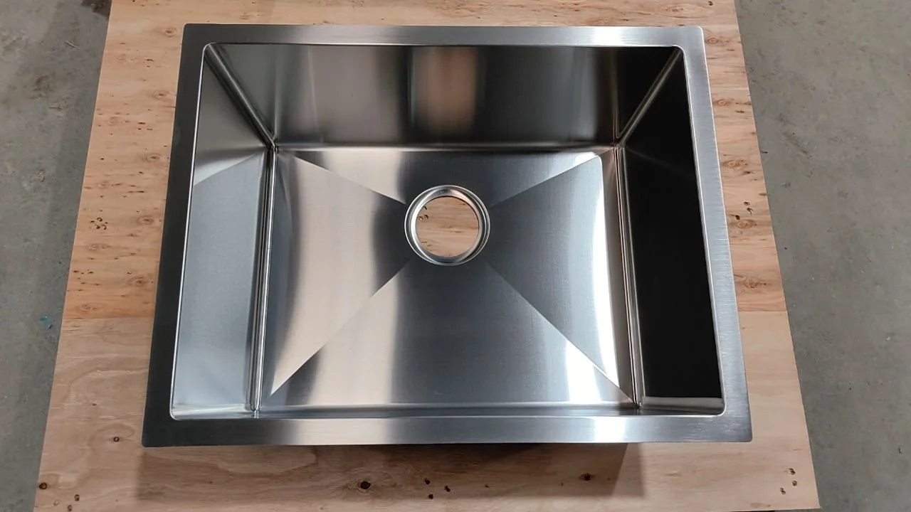 A stainless steel kitchen sink installed on a wooden countertop.