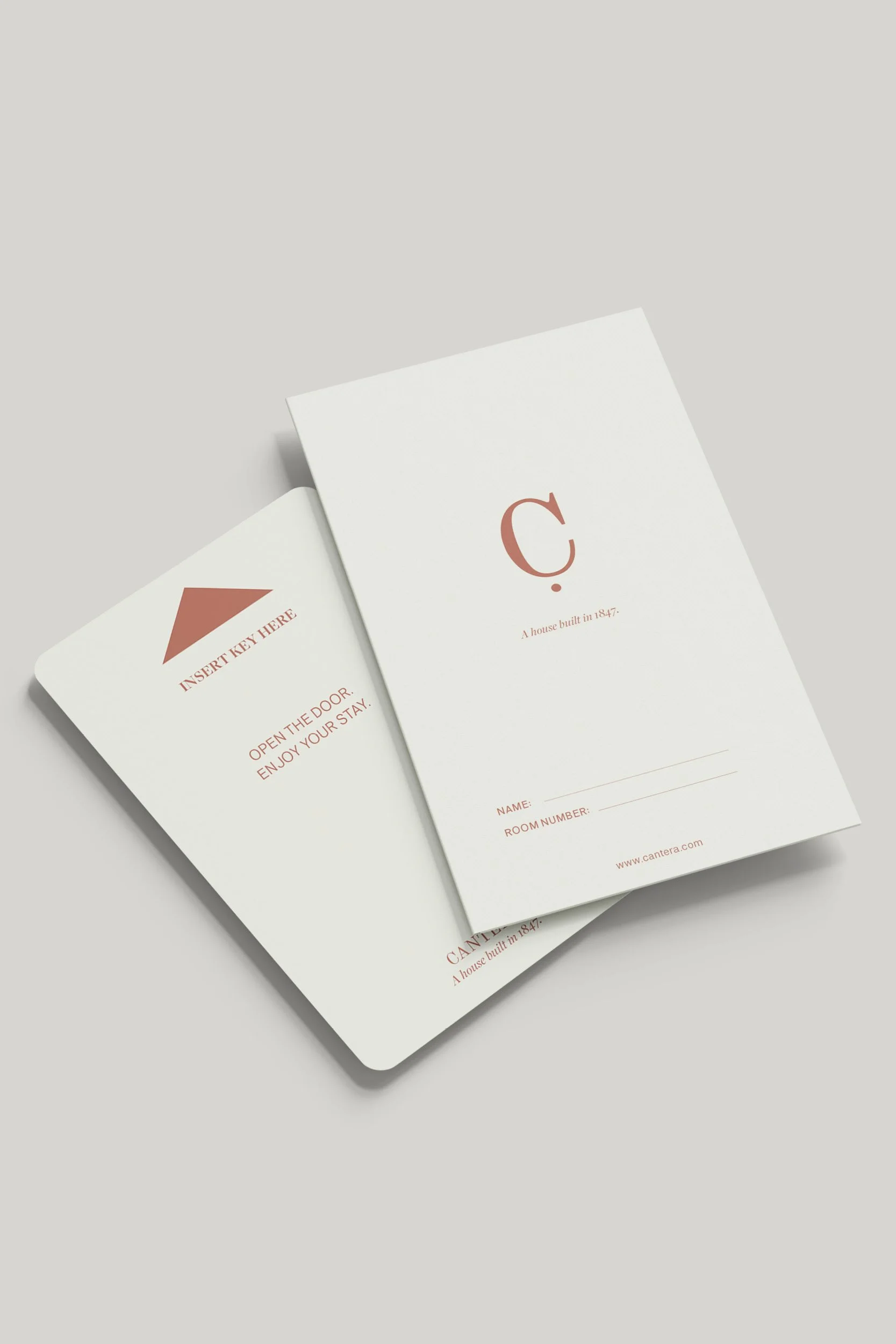 Two white cards with red text and designs, one partially overlapping the other, on a light gray background. The visible card features a large letter 'C' and an address on the bottom, while the other card has a geometric shape and the words 'INSERT KEY HERE'.