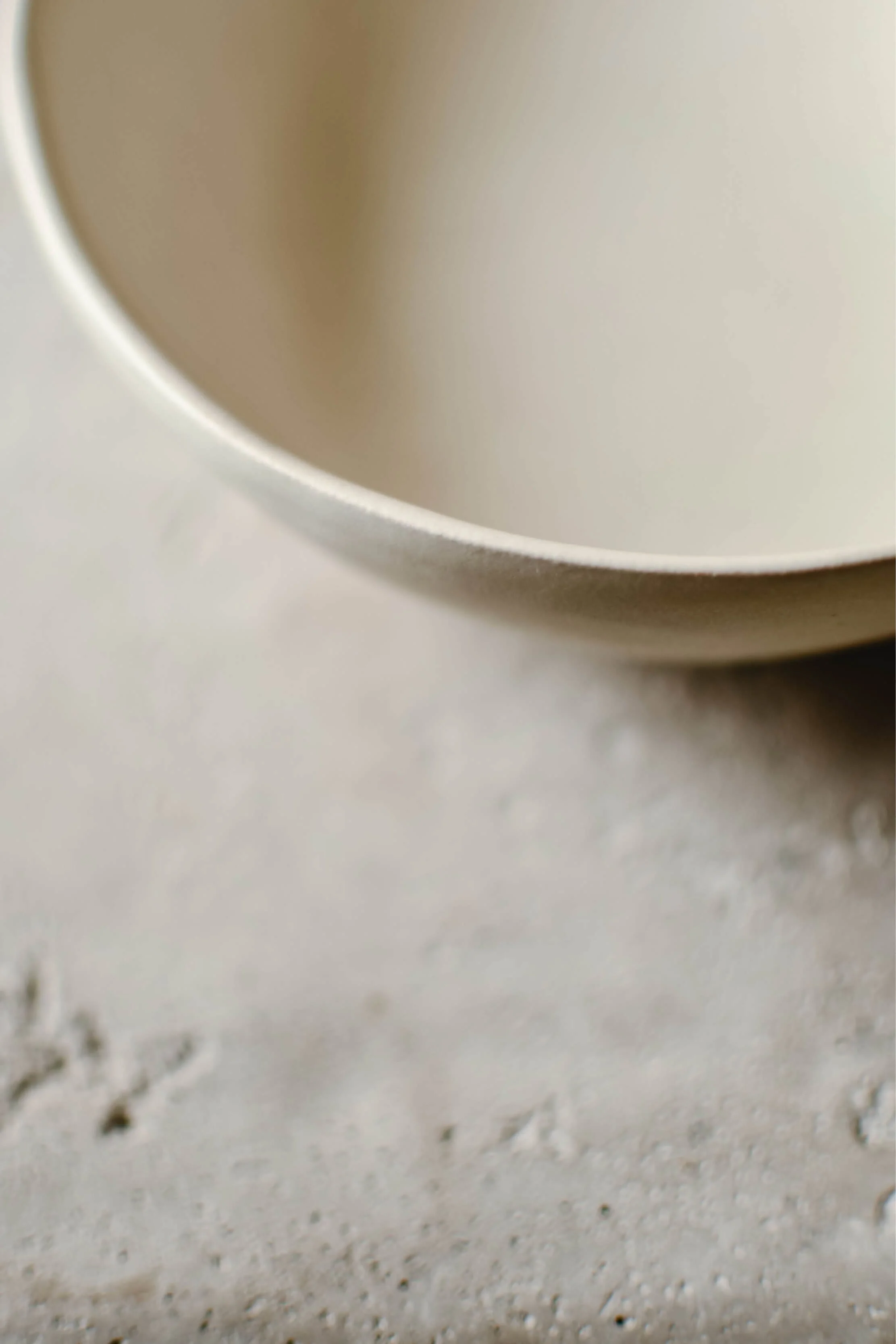 Close-up view of the interior of a white ceramic cup sitting on a textured surface.