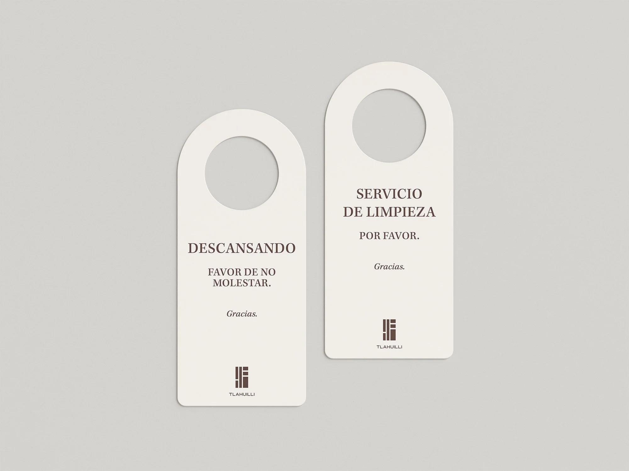 Two white cards with text in Spanish, one says 'Descansando' and the other says 'Servicio de limpieza por favor', both with 'Gracias' at the bottom, placed on a gray surface.