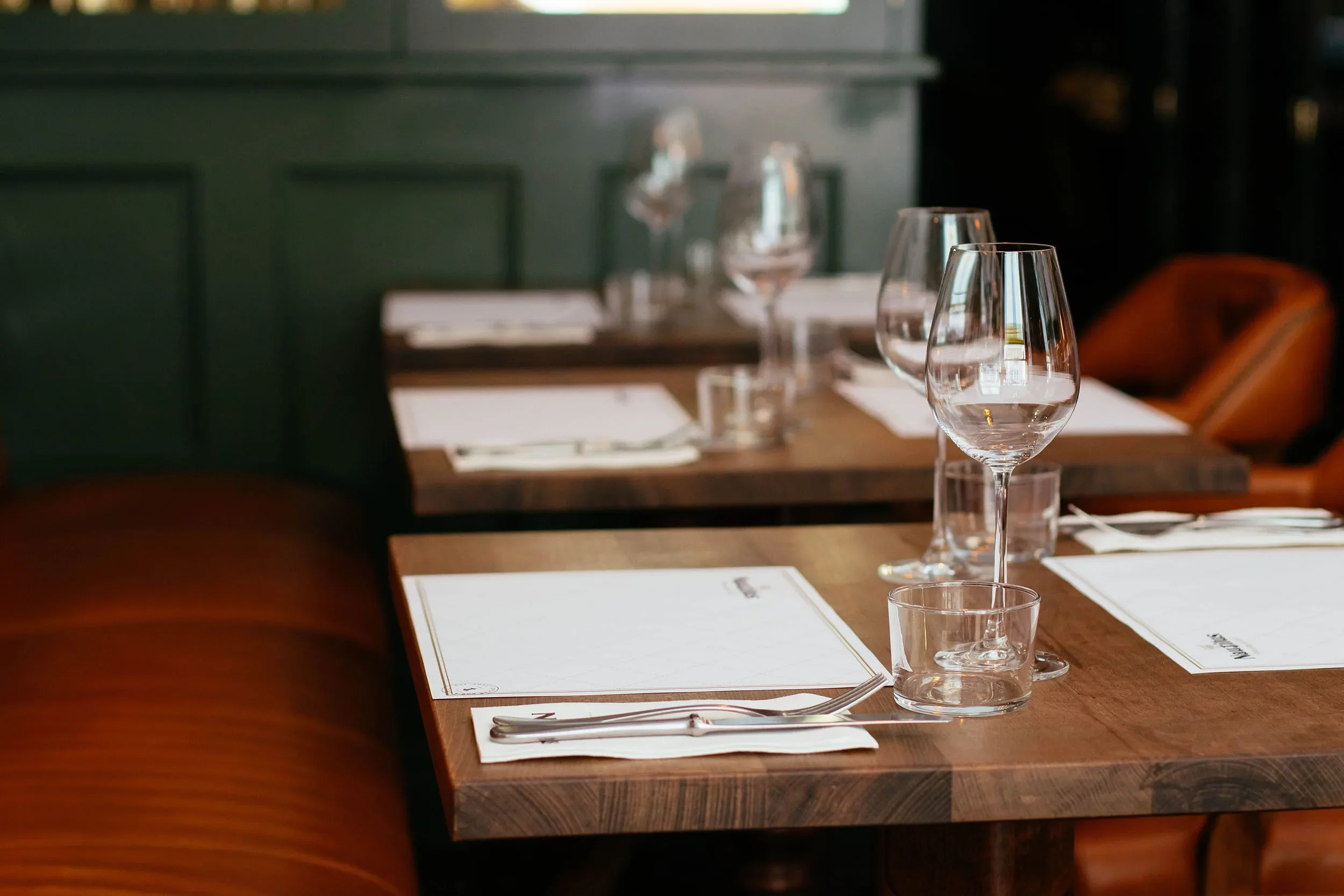 Elegant restaurant table setting with menus and glassware — the visual touchpoints that shape restaurant branding beyond social media
