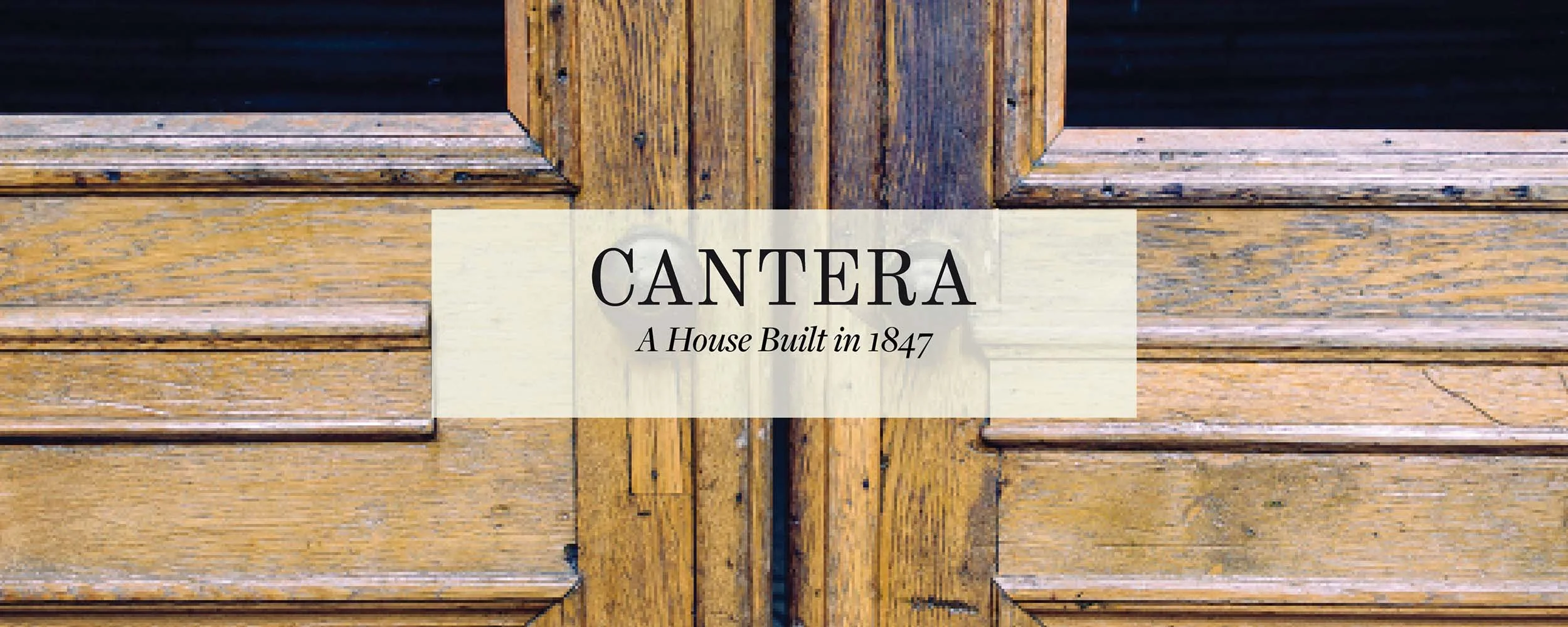Close-up of a wooden door with a sign that reads "CANTERA A House Built in 1847" overlaying the center.