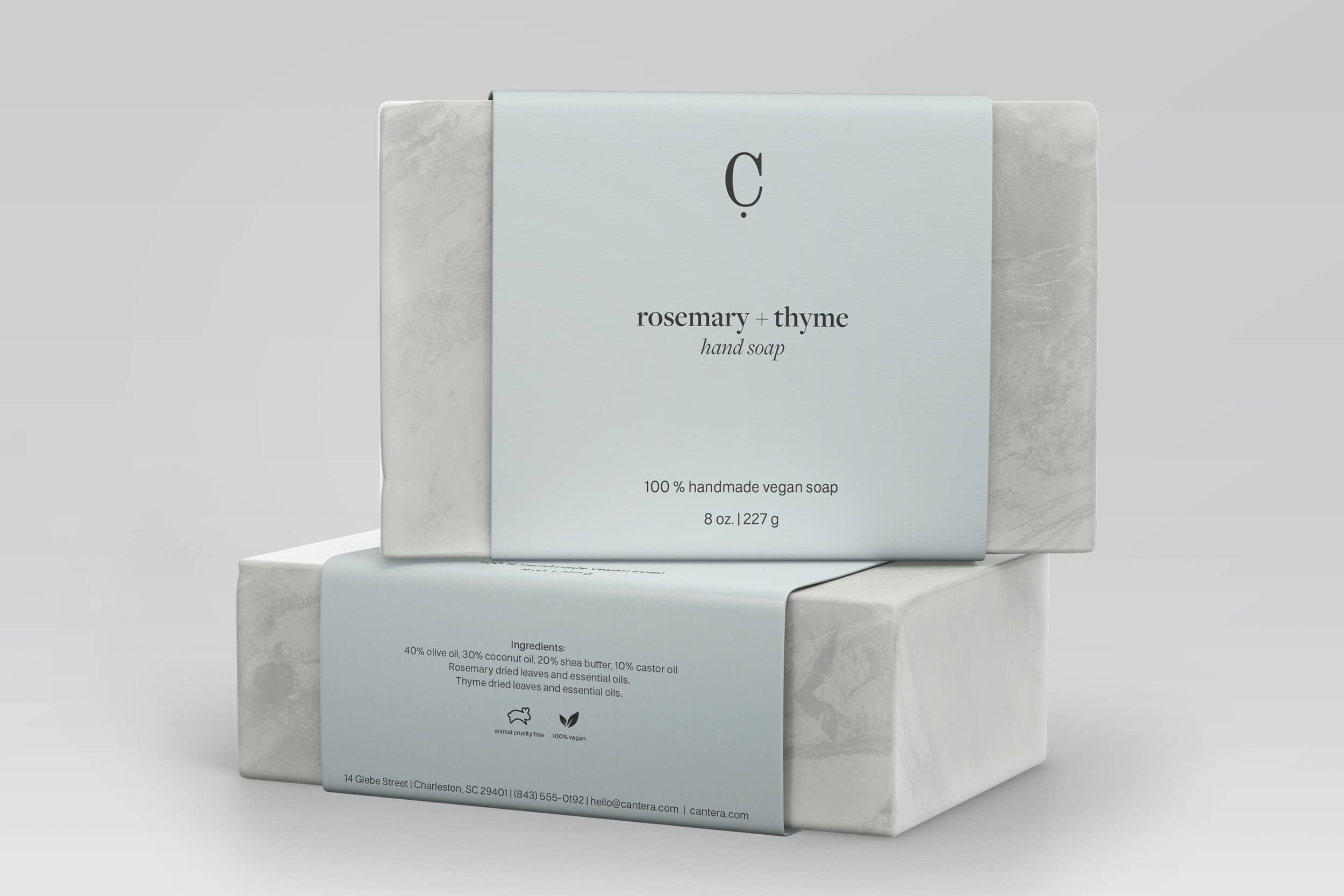 Front view of a bar of rosemary and thyme scented handmade vegan soap with minimalist white and light blue packaging.