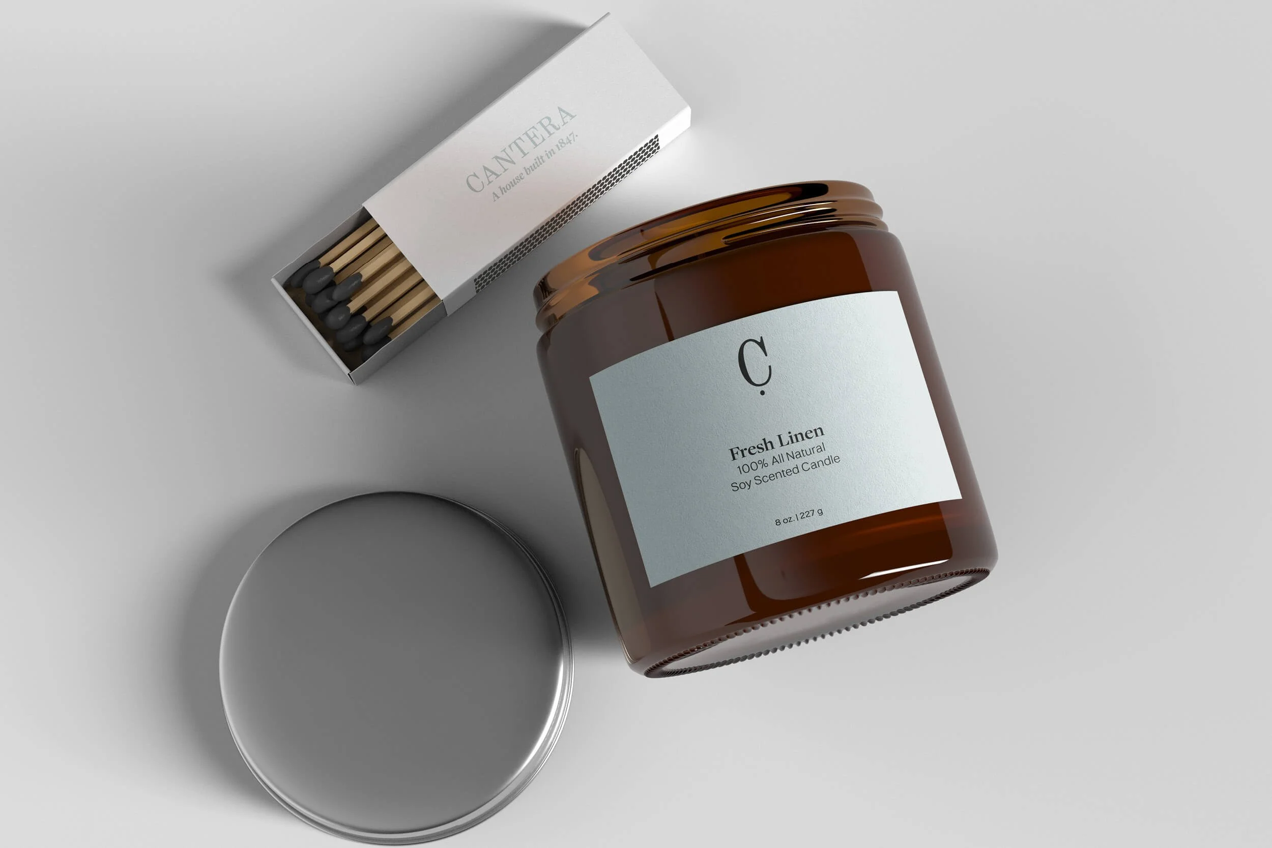 A brown jar labeled 'C. Fresh Linen 100% All Natural Soy Scented Candle' next to an open box of matches and a small white bowl on a gray surface.