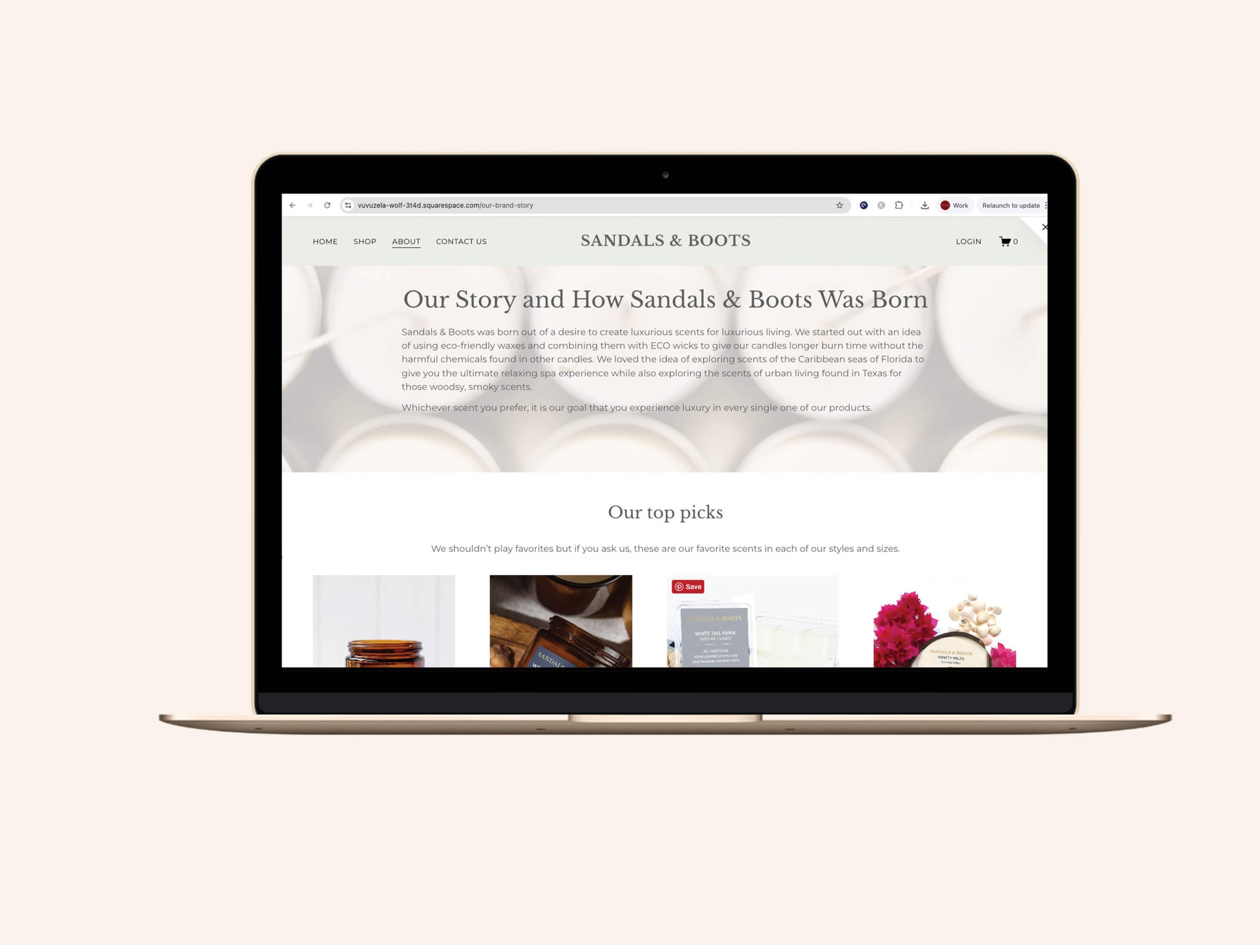 Screenshot of the Sandals & Boots About page displayed on a gold MacBook laptop, showing the brand story section with a candle flat-lay hero image and overlaid copy, followed by an "Our Top Picks" product carousel featuring four candle products parti