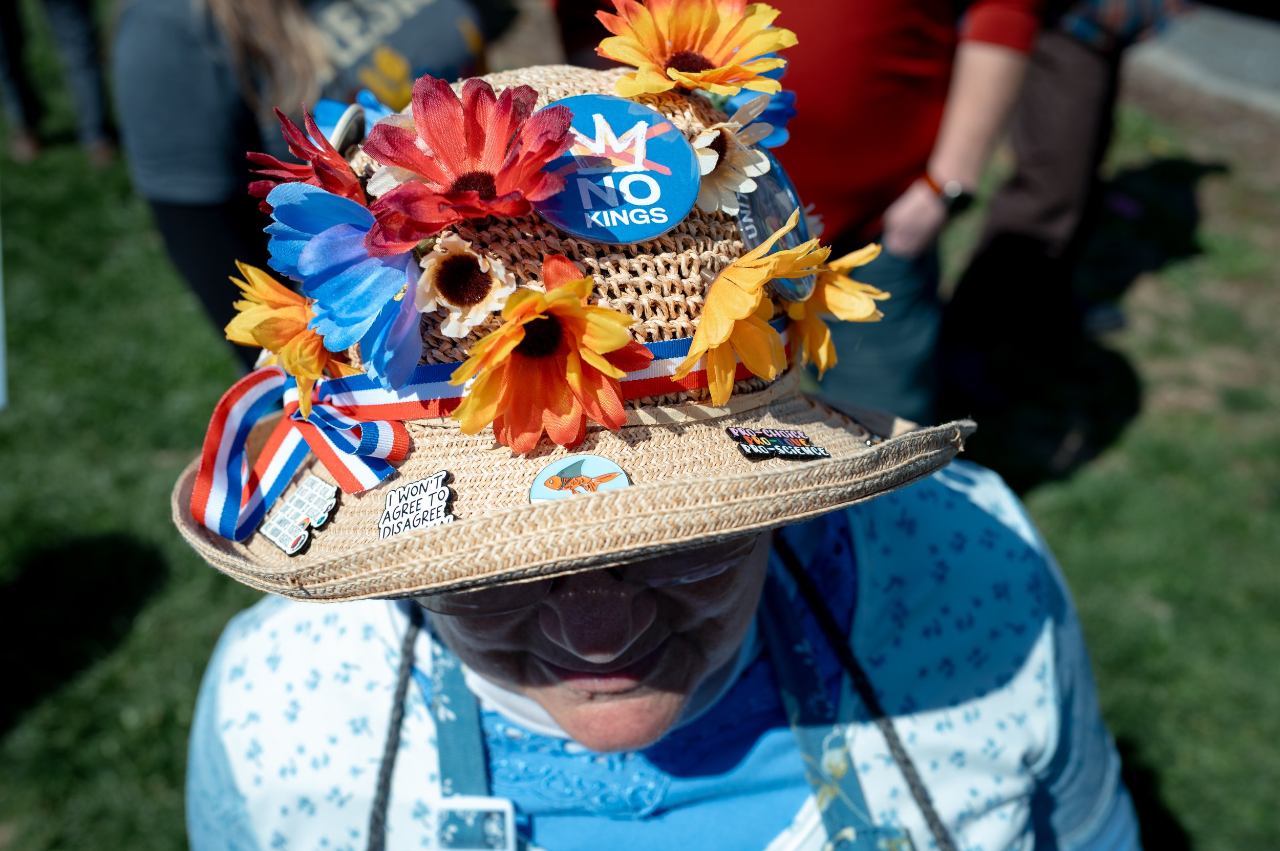 A member of the Rockingham Raging Grannies, a group known for singing protest songs, wears a hat decorated with anti–Donald Trump pins during a demonstration.