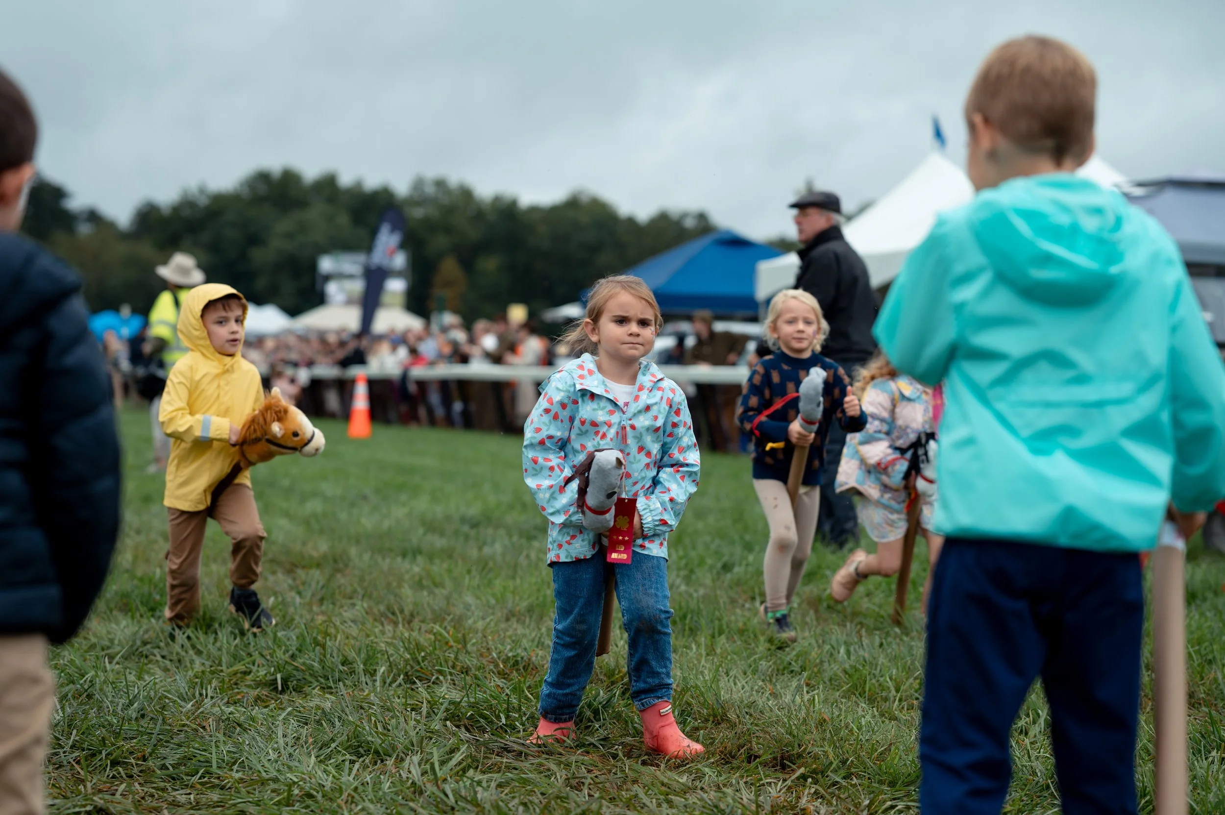 Children race with stick horses across the track between steeplechase races during the Foxfield Fall Races.