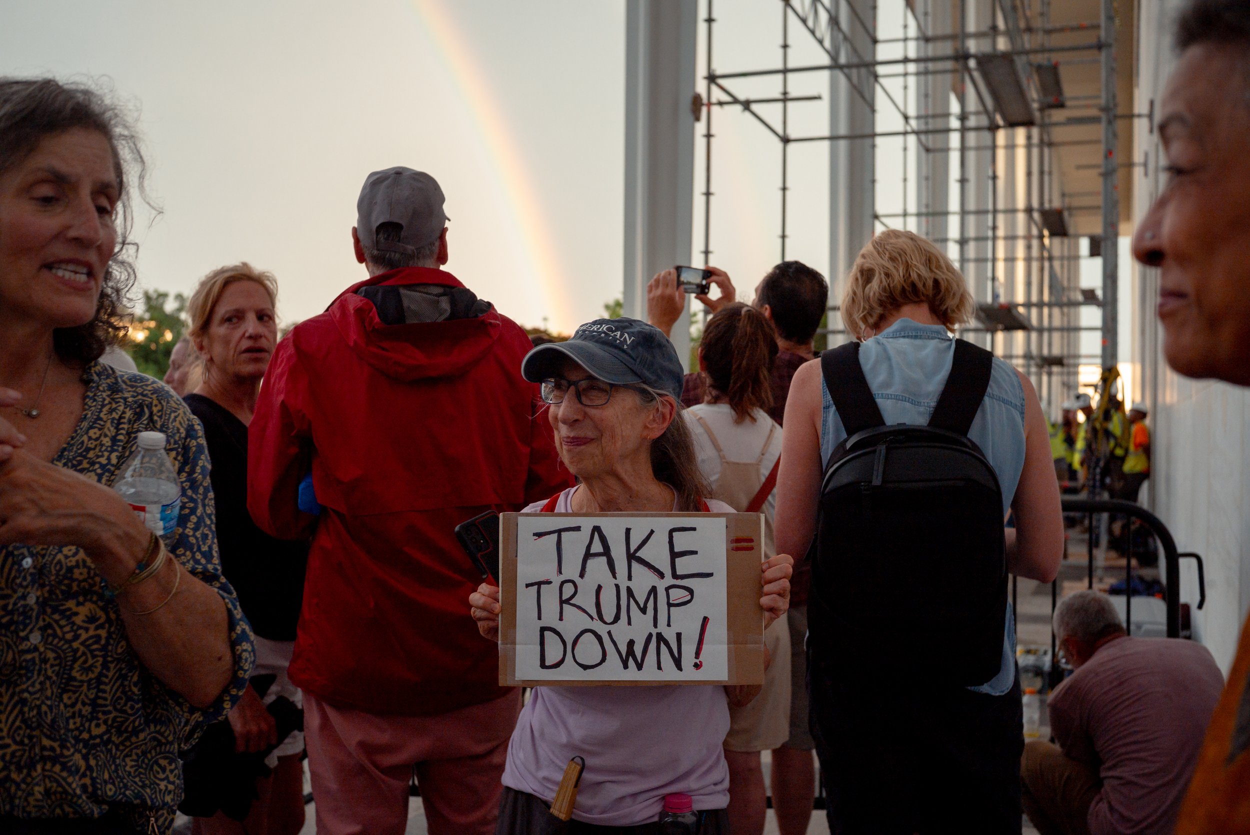 Residents and tourists gather outside the Kennedy Center in Washington, D.C., watching workers assemble scaffolding around the building.