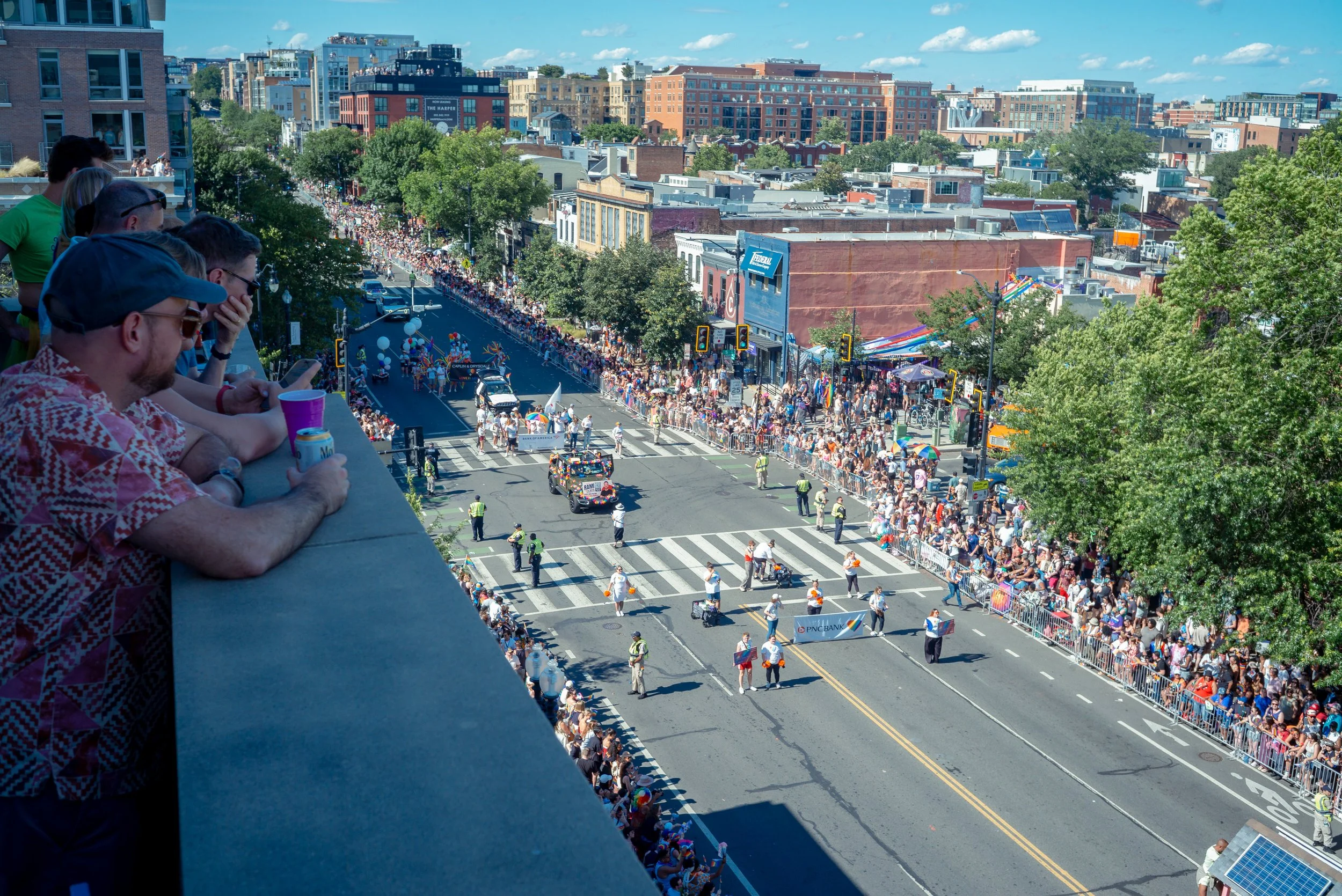 Onlookers gather on a rooftop in Washington, D.C., after leaving a nearby work event early to watch the Capital Pride Parade pass through the city. Thousands lined the streets for one of the region's largest LGBTQ+ celebrations. June 19th, 2026. 
