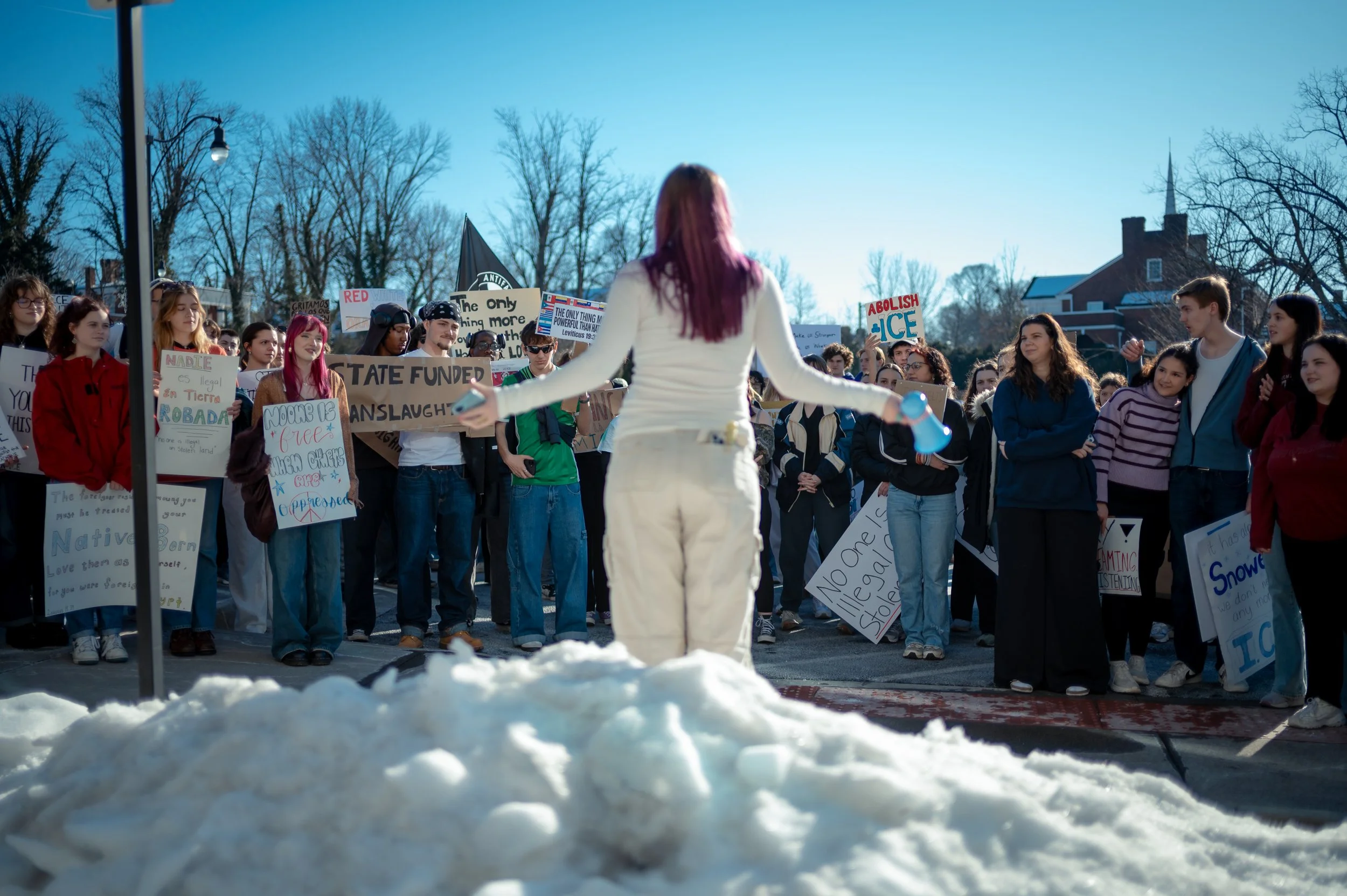 A speaker stands on a hill of snow while protesting ICE agents in Harrisonburg  VA at City Hall.