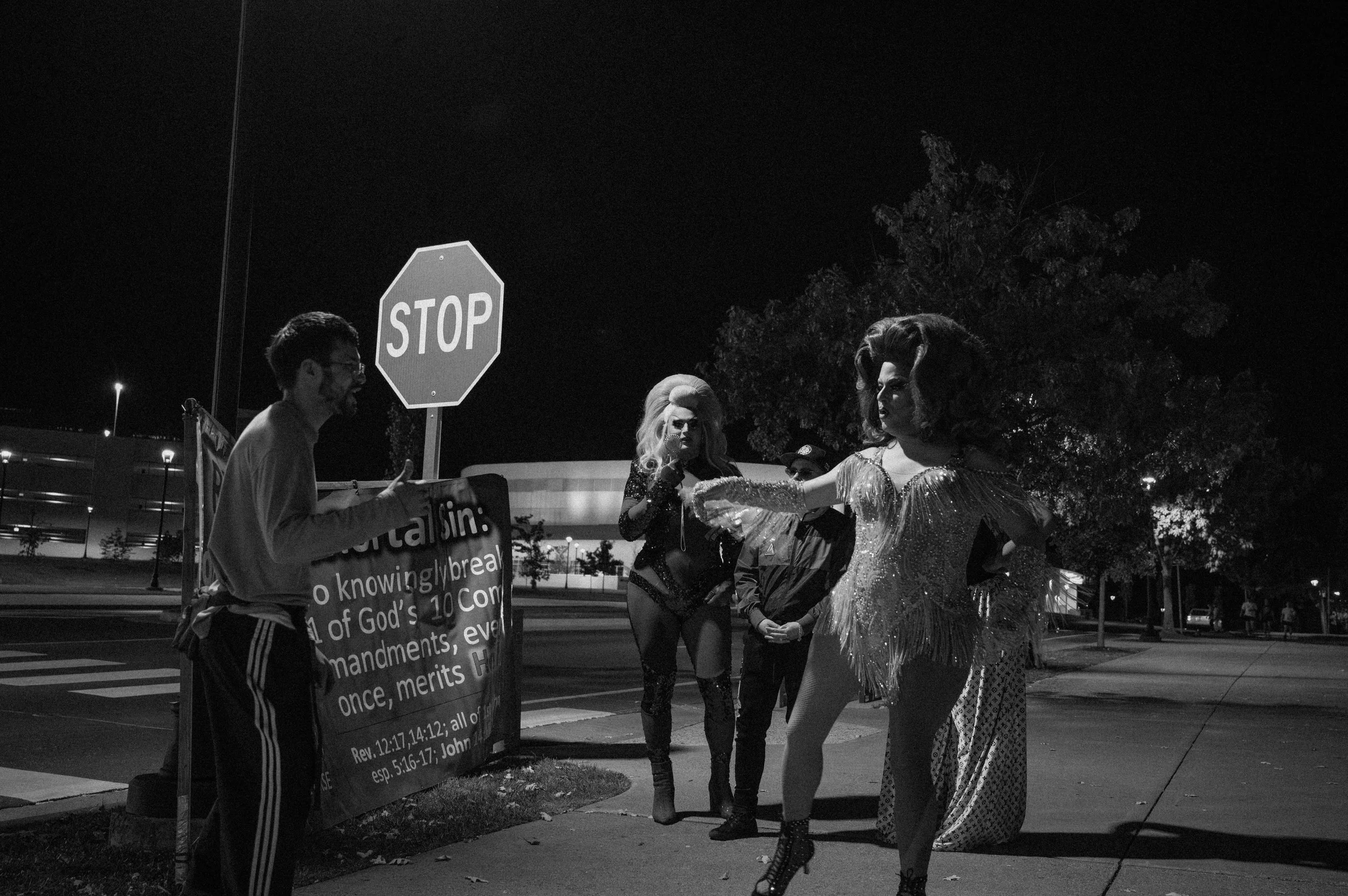 Four Harrisonburg drag queens dance in front of a protestor outside JMU. 