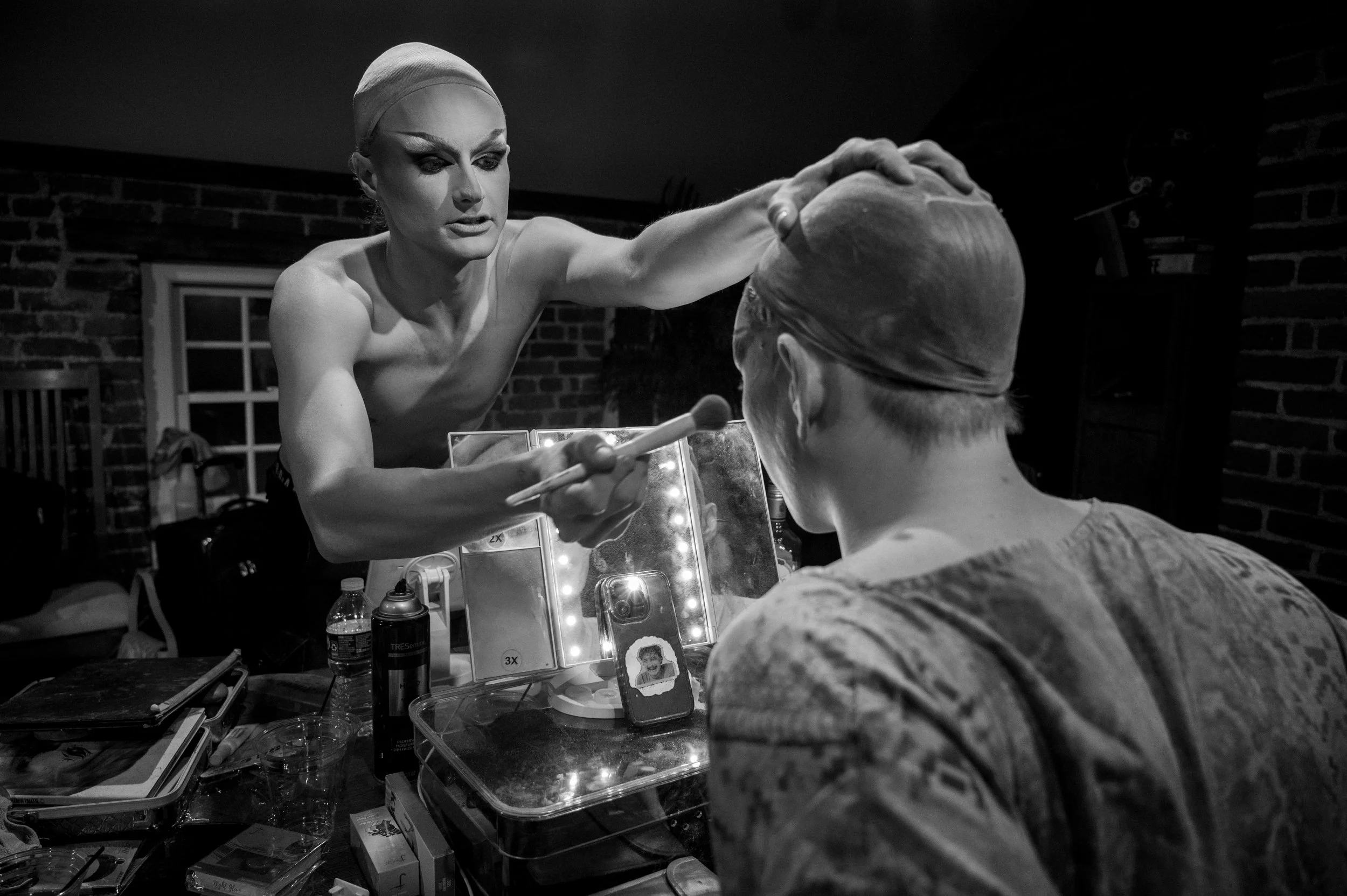 Climaxxx reaches across the table and helps Nick with his makeup.