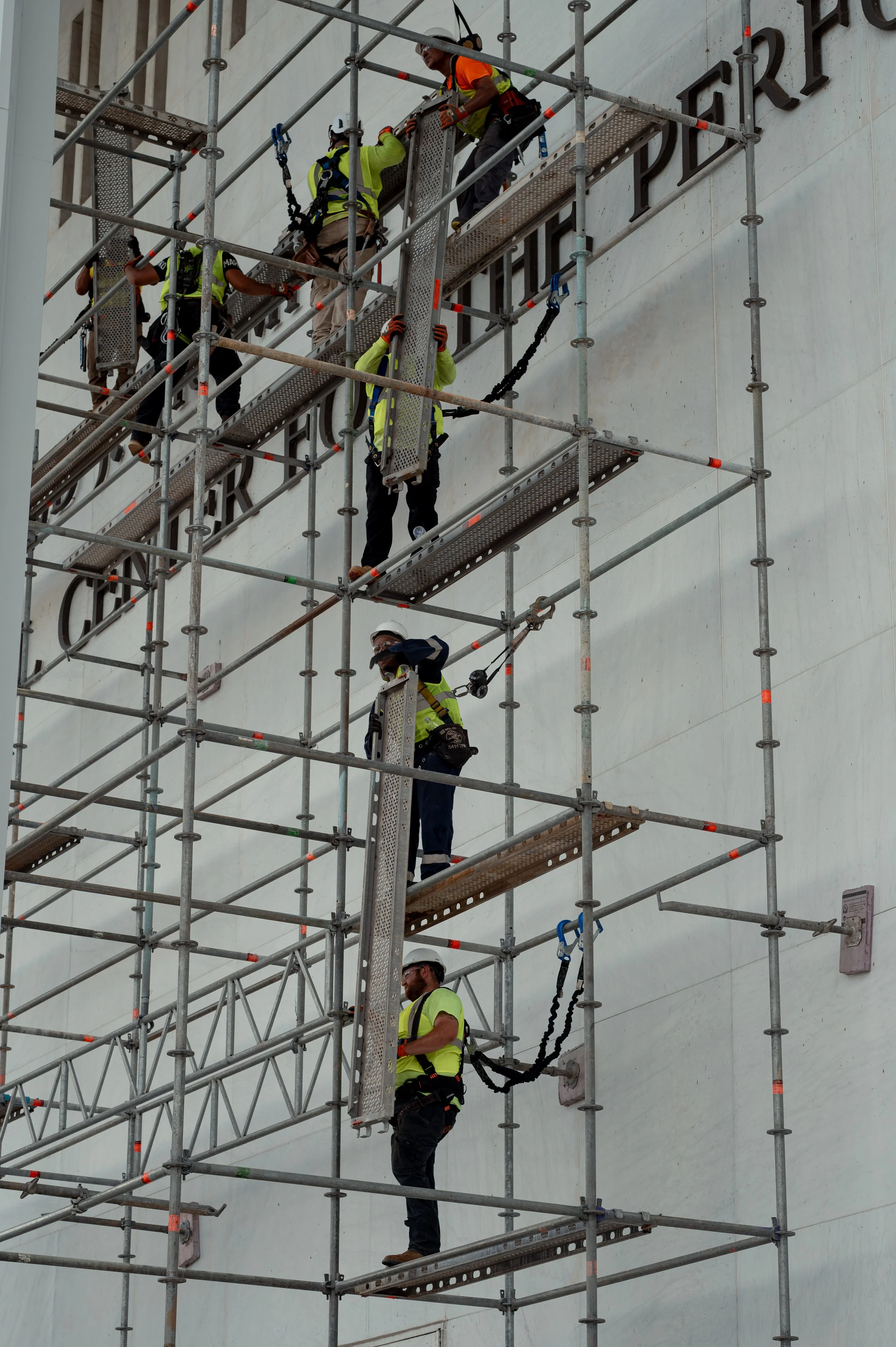 Workers erect scaffolding outside the John F. Kennedy Center for the Performing Arts in Washington, D.C. Crews prepared the structure for maintenance work as onlookers gathered nearby.