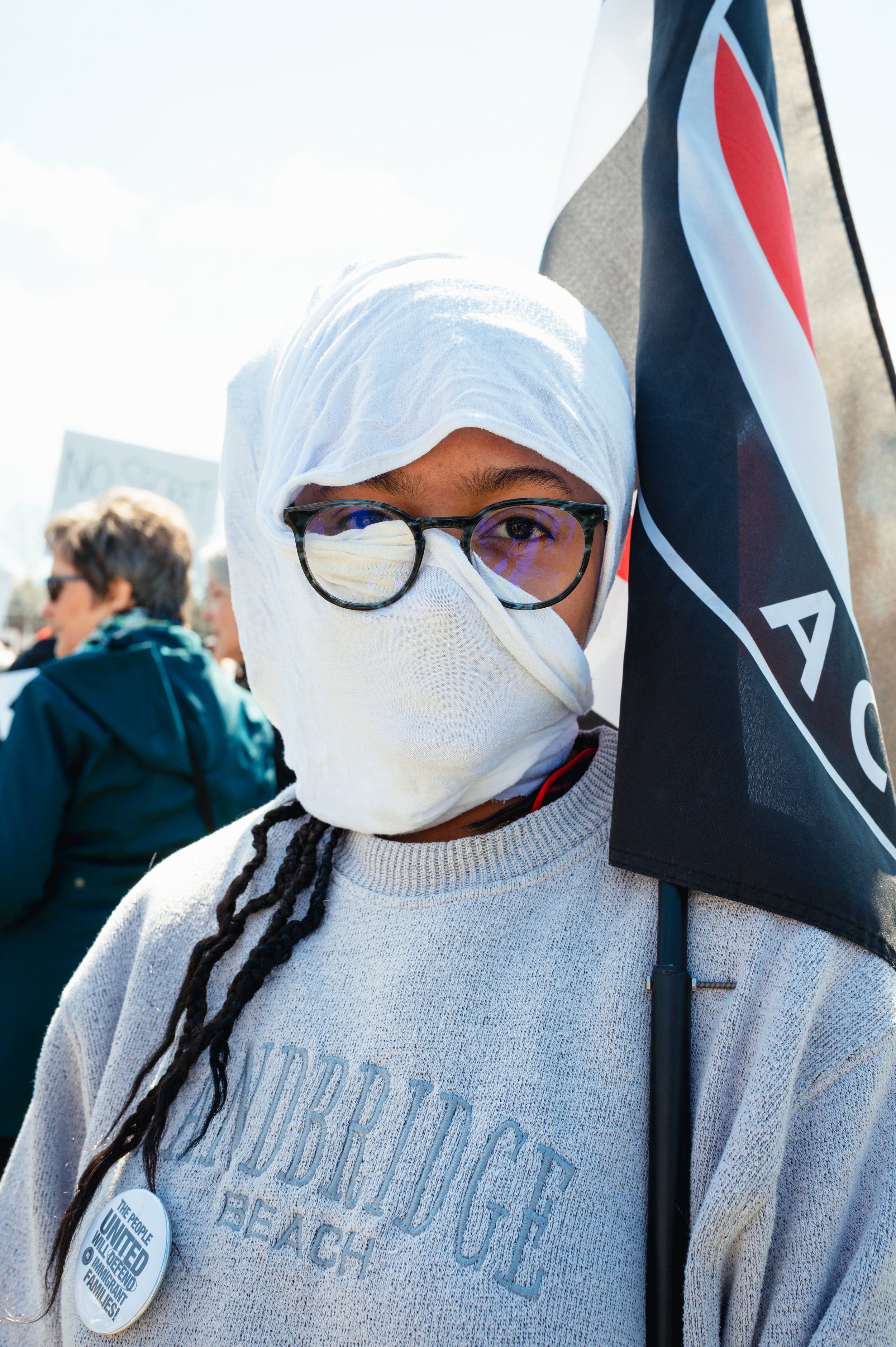 One protestor covers her face and holds up an Antifa flag.