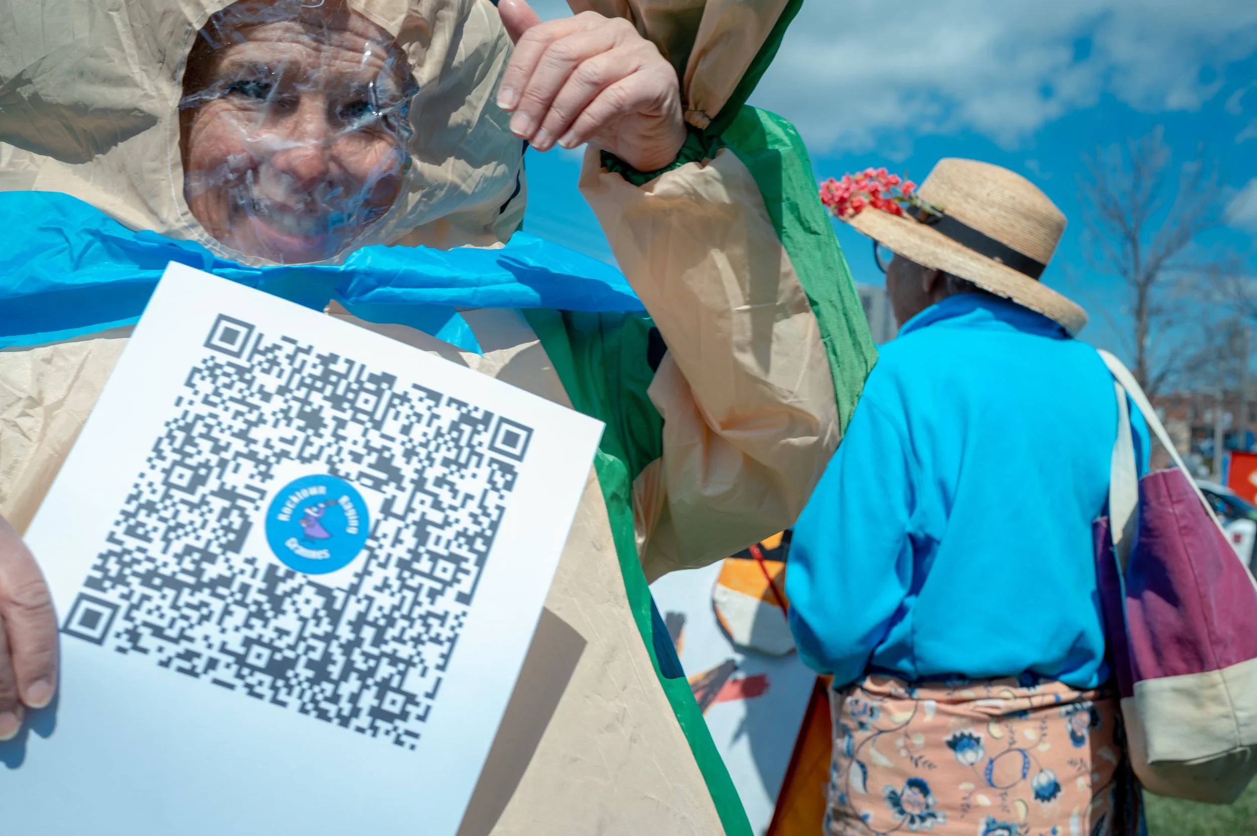 A woman wearing an inflatable frog costume holds up a scannable sheet during the protest.