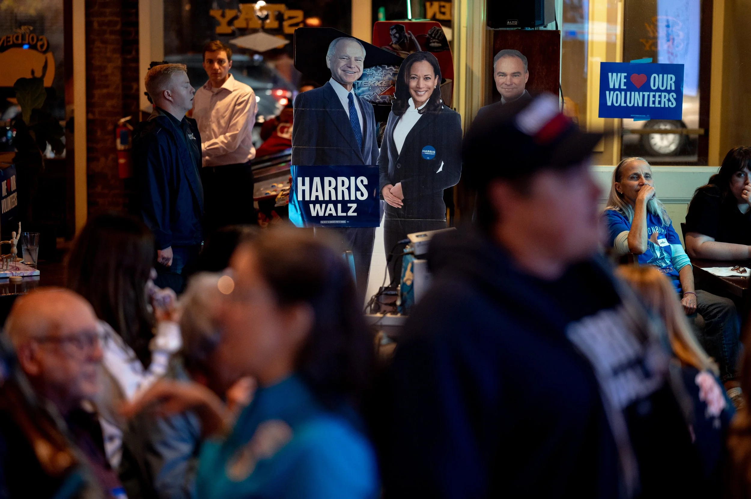 A cardboard cutout of Kamala Harris and Tim Walz stands above the crowd at a Democratic election watch party in 2024. Attendees moved through the room as reactions shifted throughout the night. 