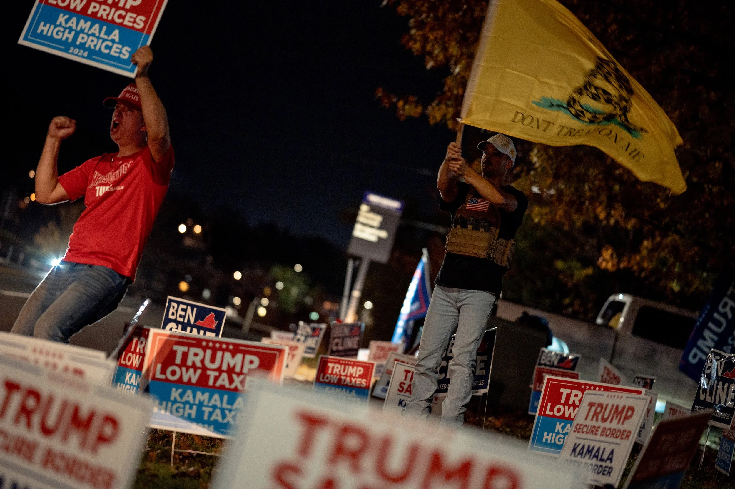 Two James Madison University baseball players stand outside their house waving Trump signs and flags on election night. Cars passing through the neighborhood honked as students gathered outside nearby homes following the results.