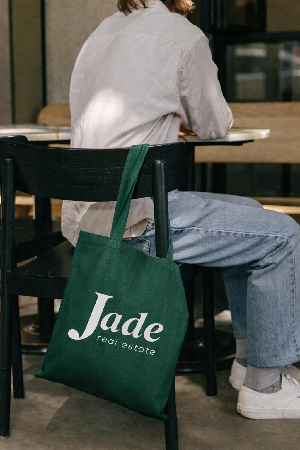 Jade Real Estate branded tote bag at a cafe