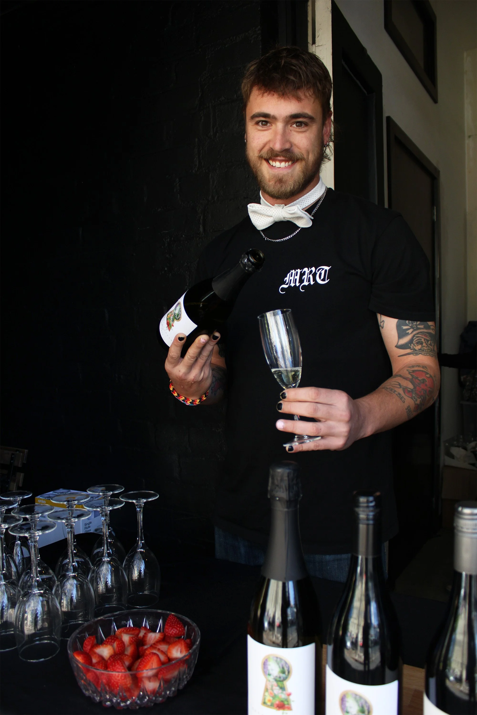 Staff member at independent fashion brand event pouring a glass of wine.
