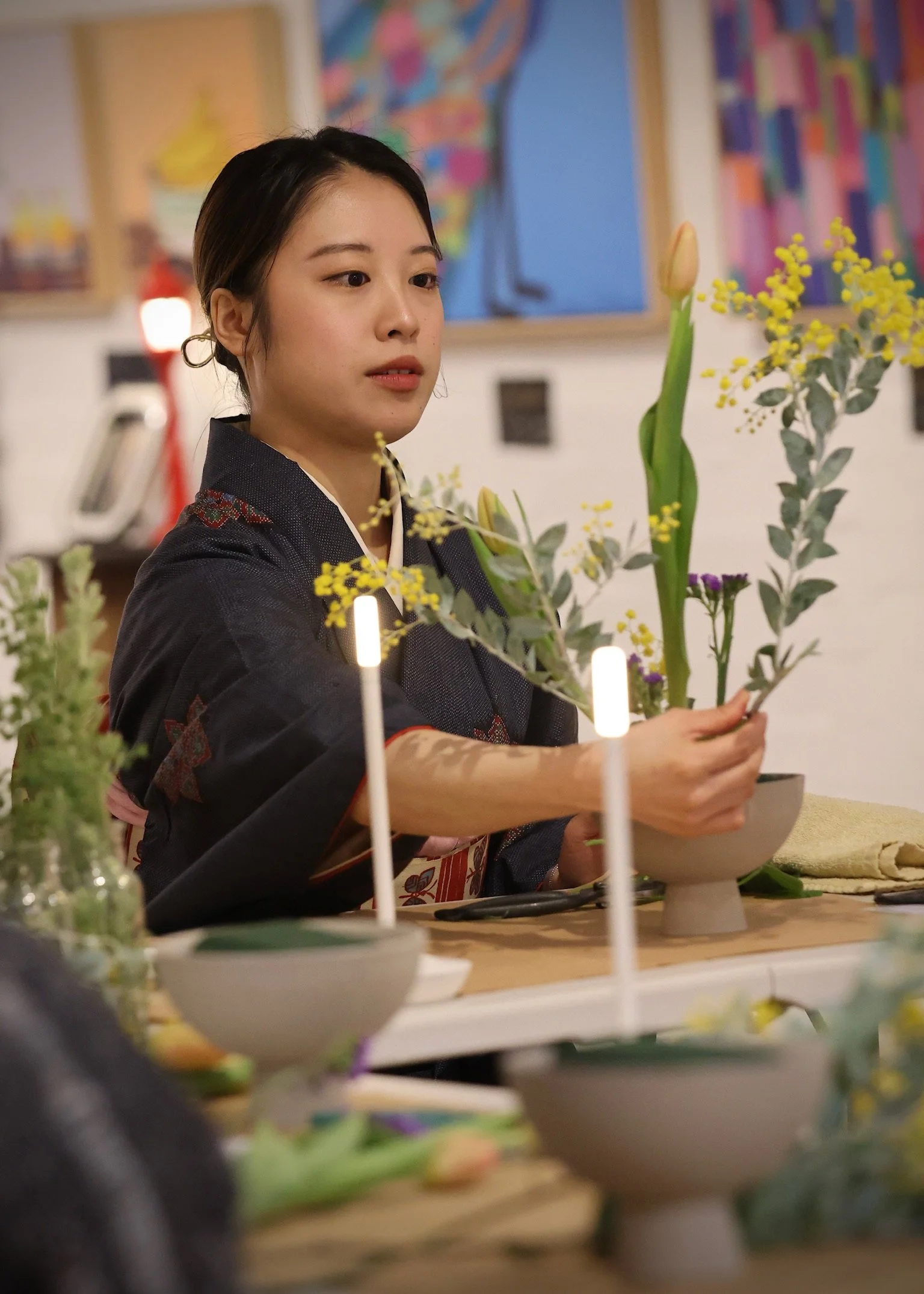 Person arranging flowers, art in background