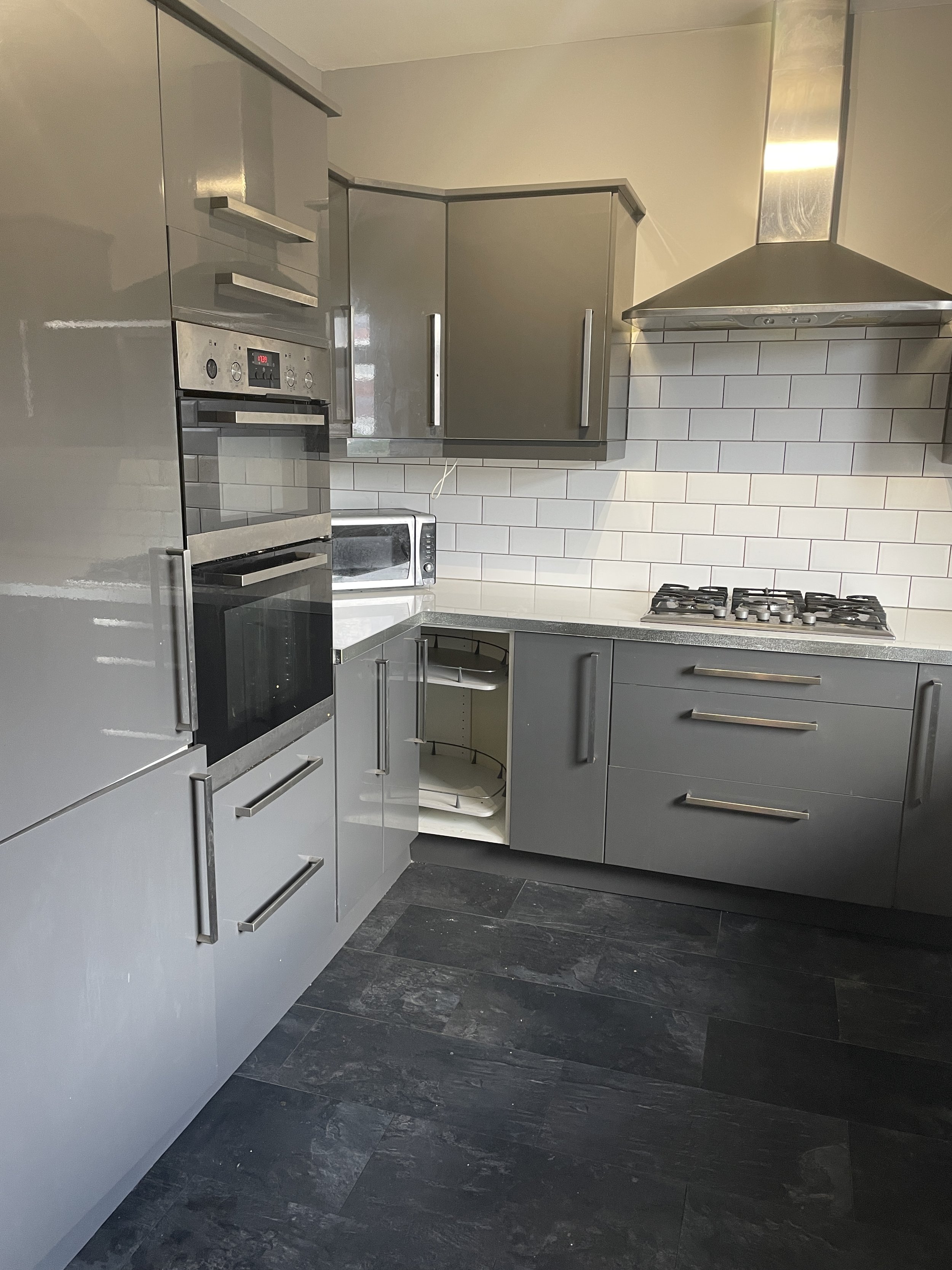 Left hand view of kitchen project with grey laminate floors and gloss grey units