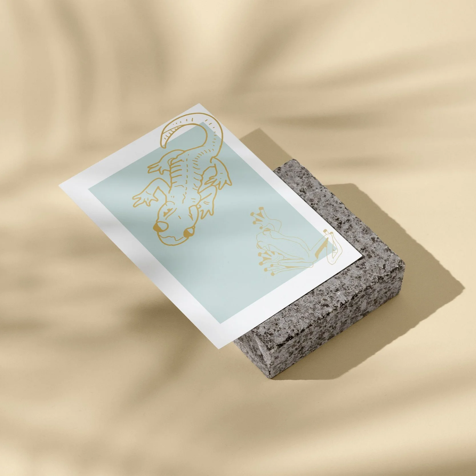 Ein gedruckter Aufkleber mit einem orangen Drachen und einem blauen Einhorn auf einer kleinen Steinunterlage auf hellem Hintergrund.