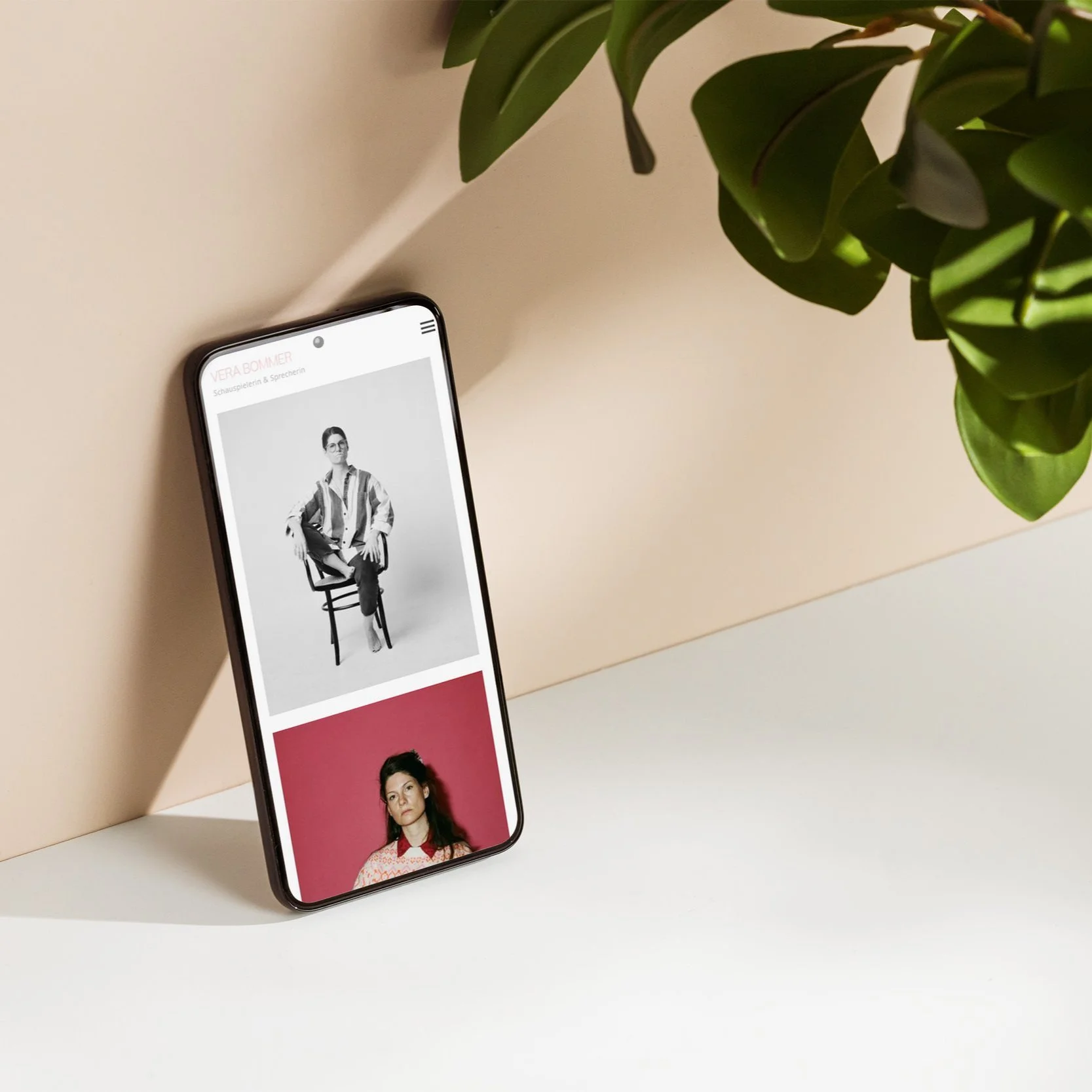 Smartphone mit Fotos von Schauspielerin Vera Bommer, auf einem Tisch mit einer Pflanze im Hintergrund.